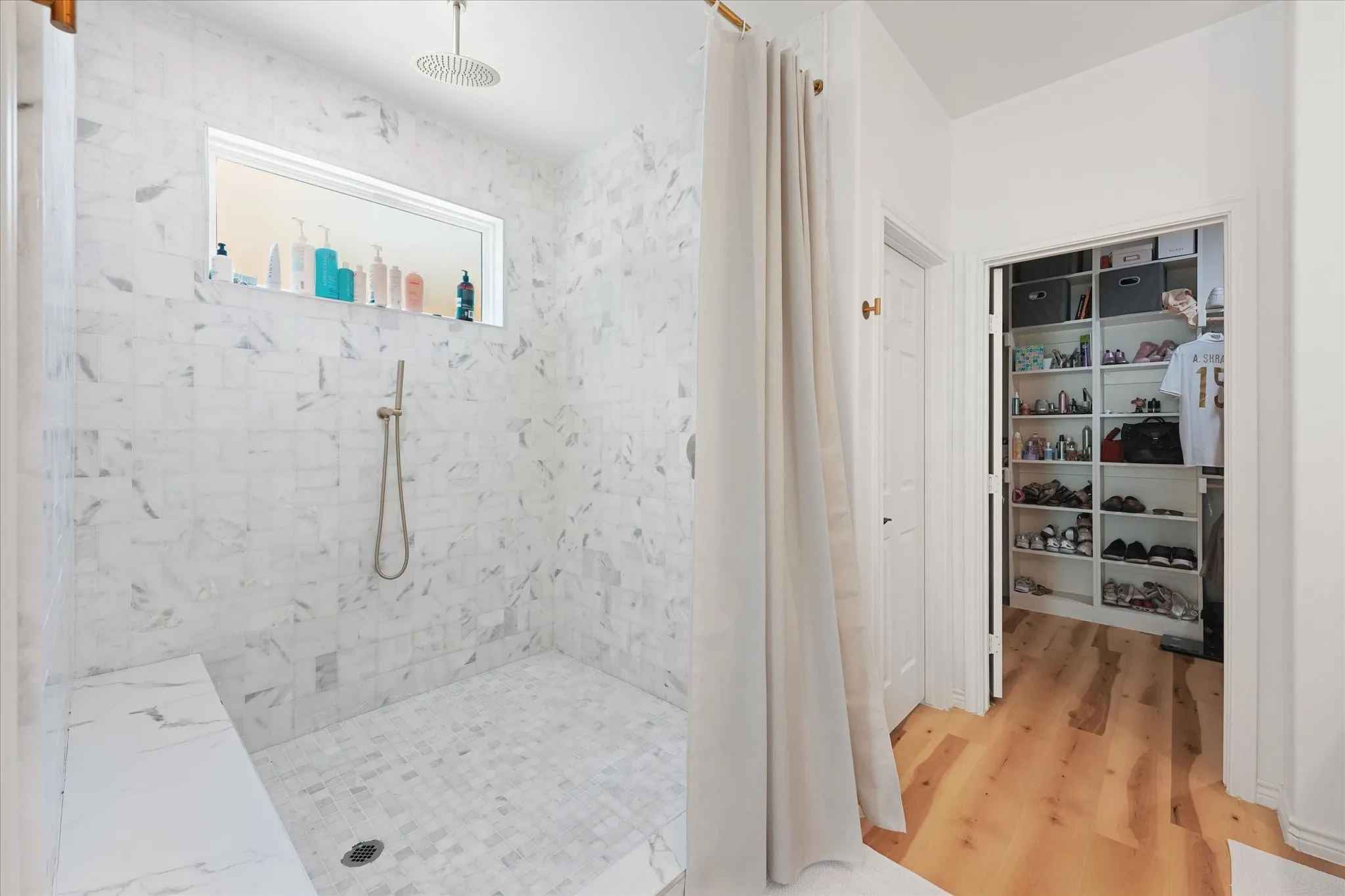 Walk-in shower with tiled walls and floor, recessed window, rain shower head, and built-in bench