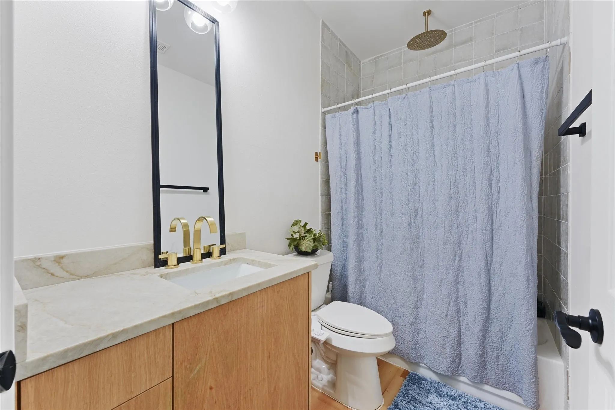 Light-toned wood-finish vanity with a built-in sink and gold-finish fixtures