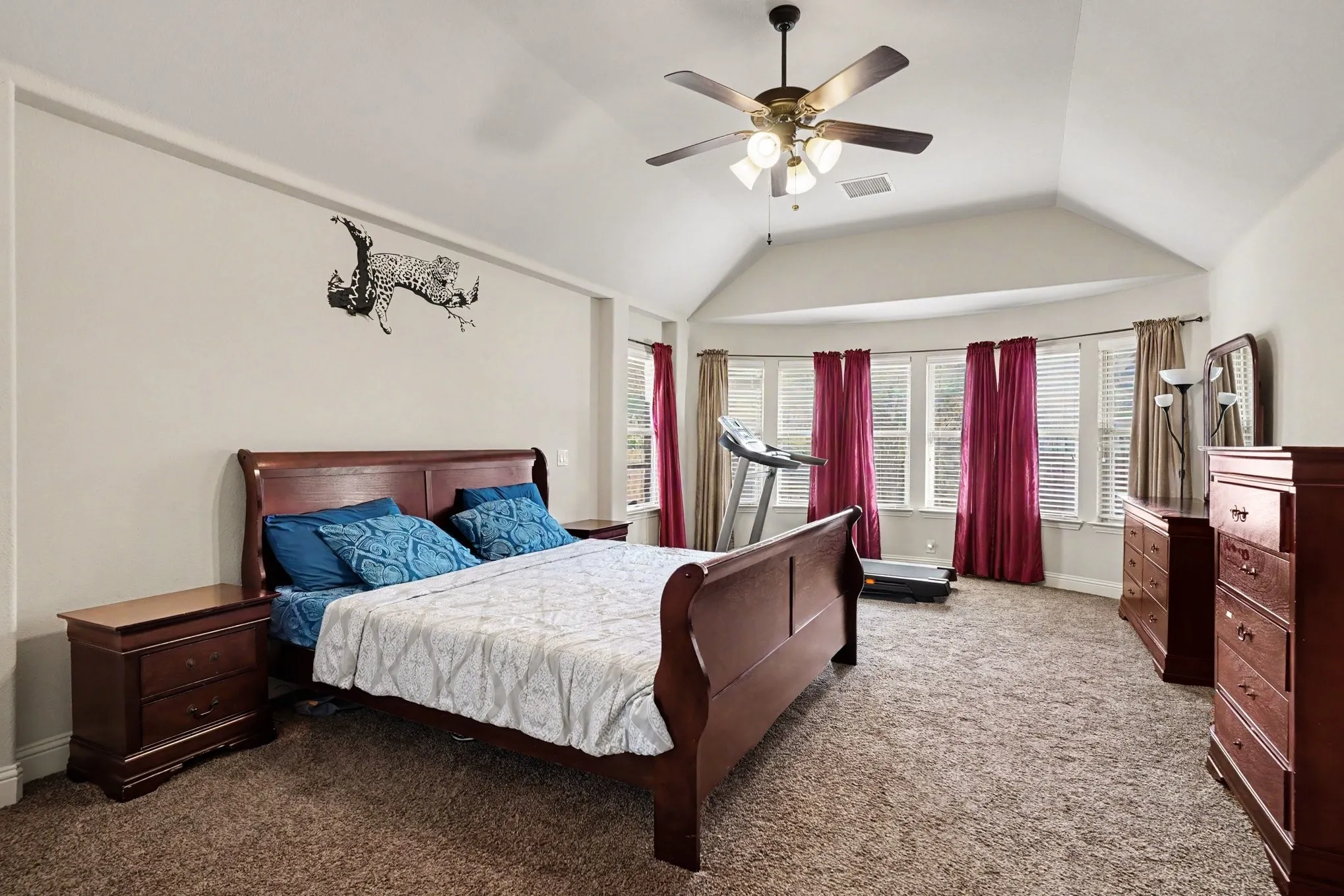 Vaulted ceiling featuring a ceiling fan with integrated lighting, bay window with multiple windows, and carpet flooring