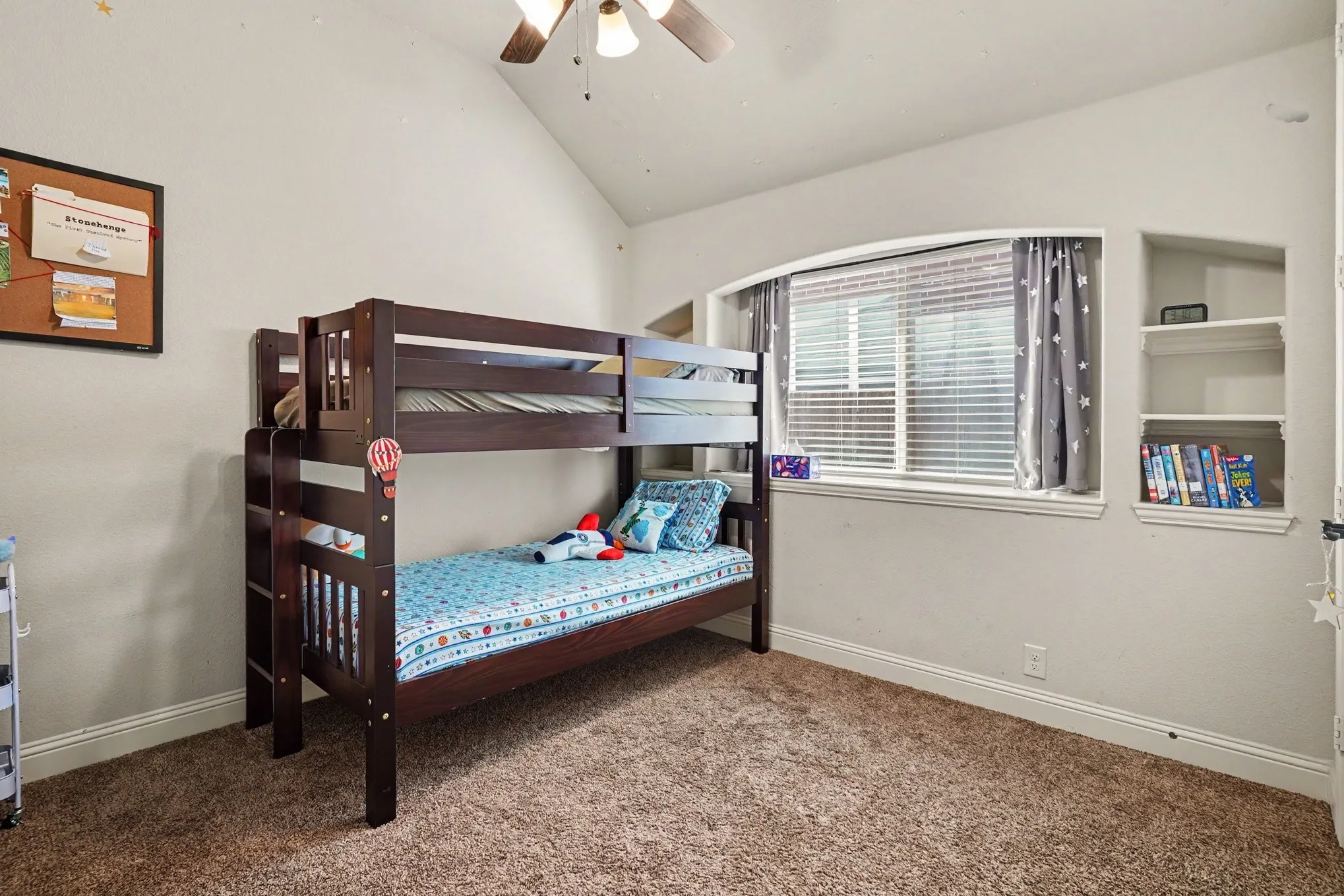Vaulted ceiling, built-in shelving, window with blinds, and carpeted flooring
