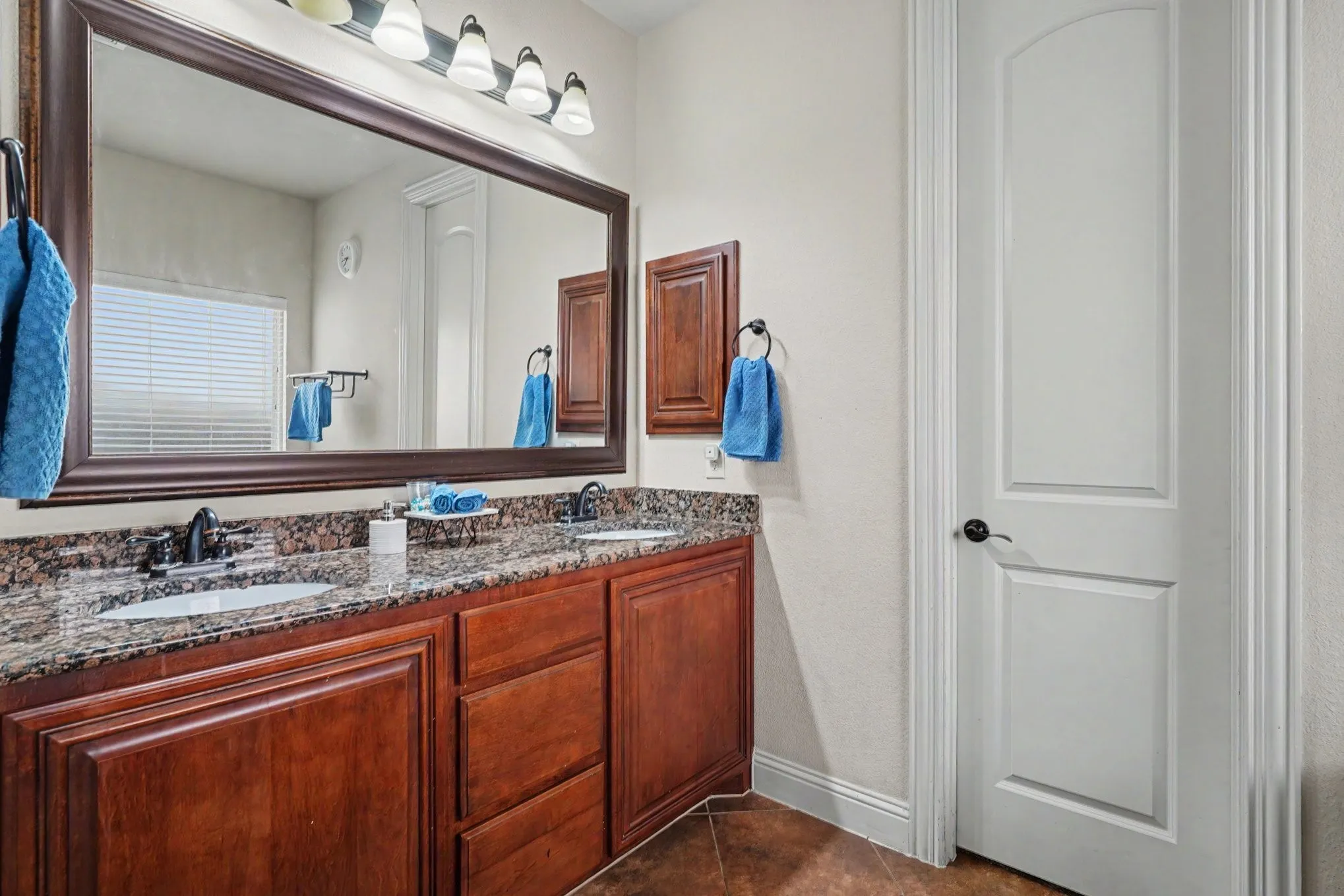 Dual vanity with dark wood-finish cabinetry, stone countertop, and undermount sinks