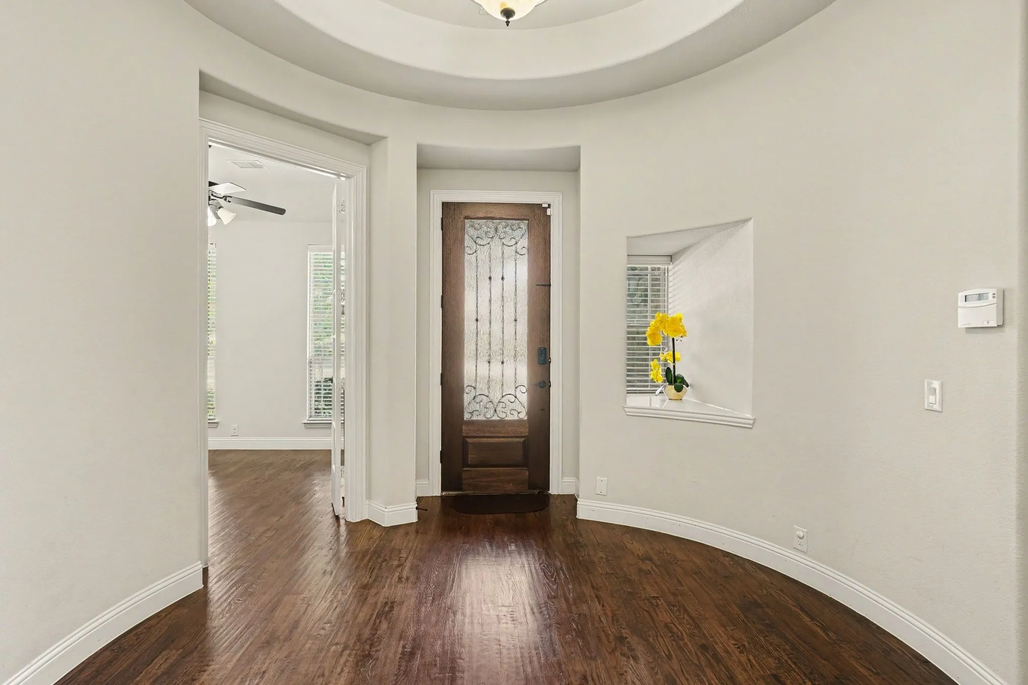Curved entryway with rich wood-finish flooring