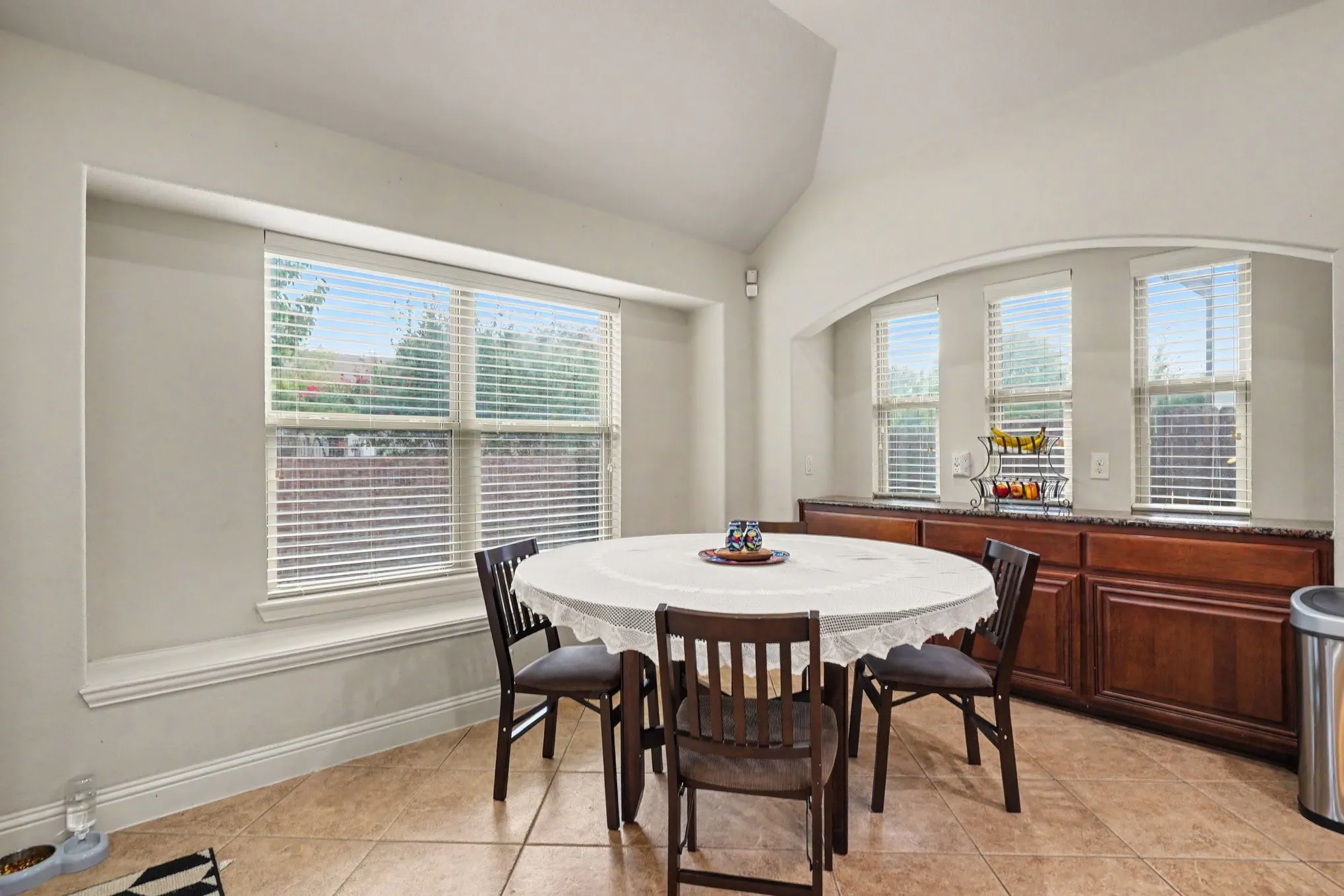 Arched architectural detail, tiled flooring, wood-finish cabinetry, built-in window seating, and multiple windows
