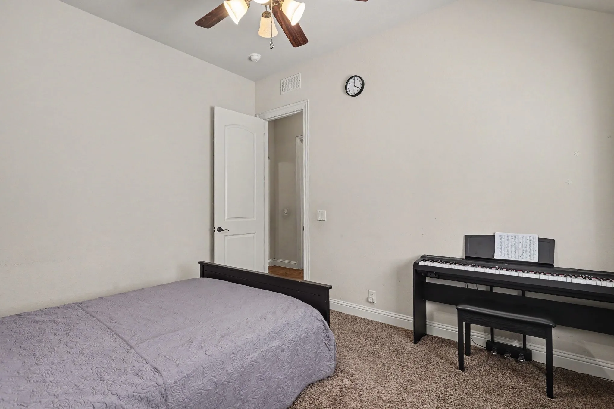 Neutral wall tones, ceiling fan with light fixture, white interior door, and carpet flooring