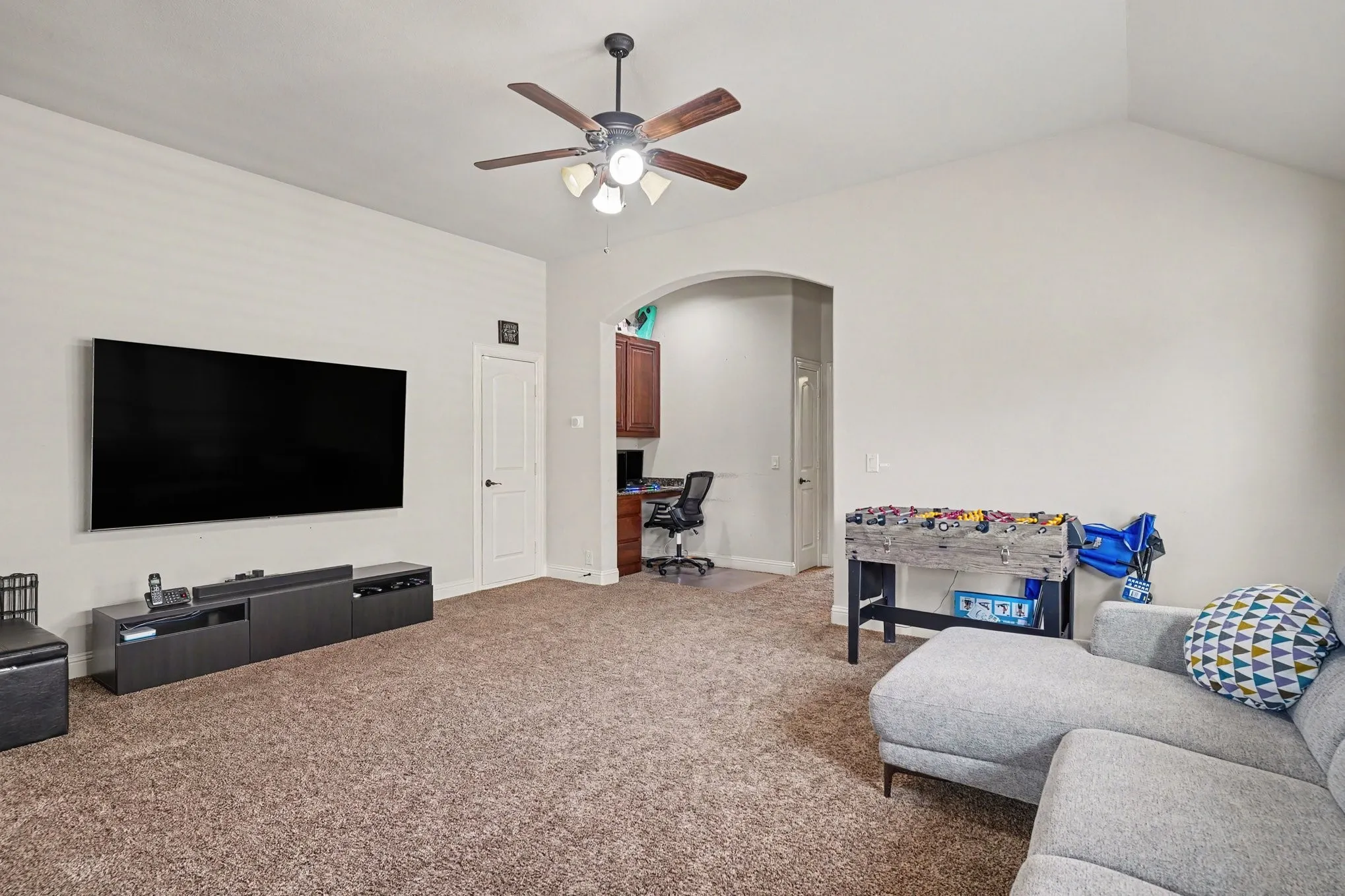 Vaulted ceiling with a ceiling fan, carpet flooring, archway, and built-in cabinetry