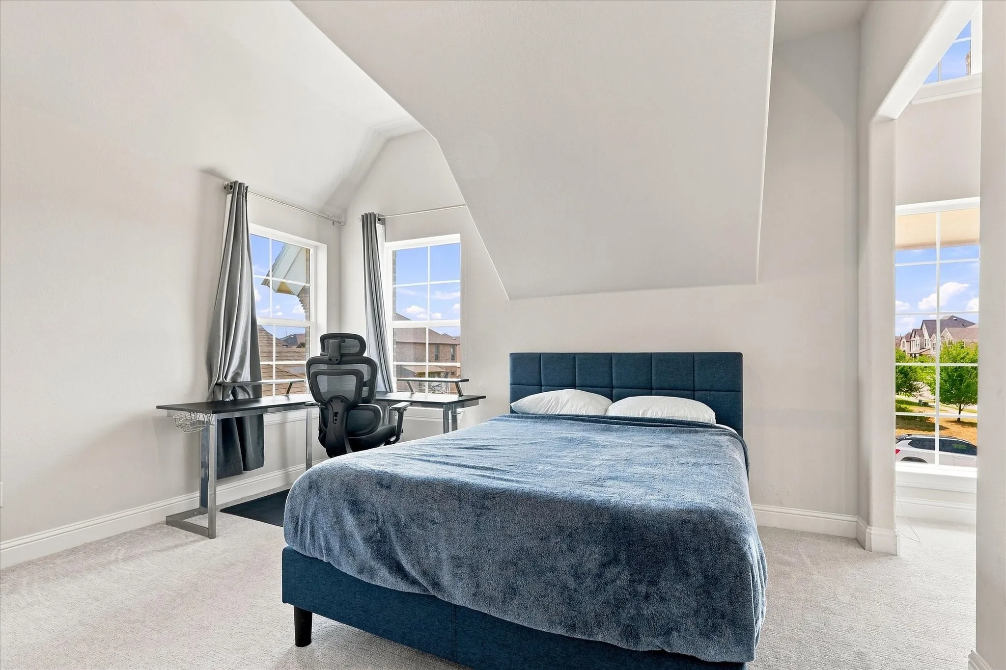 Vaulted ceiling with multiple windows and light-toned carpeting