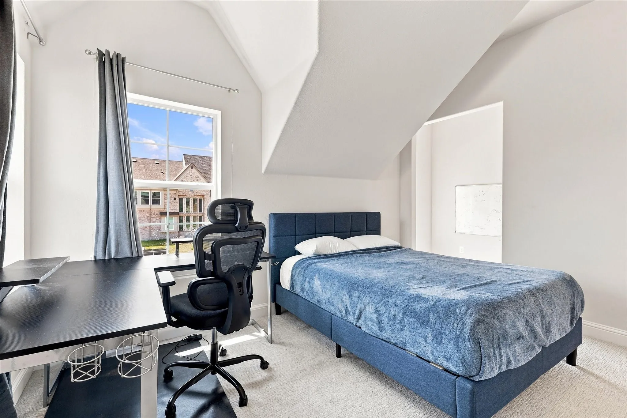 Carpeted room with a large window, sloped ceiling, and white wall finishes