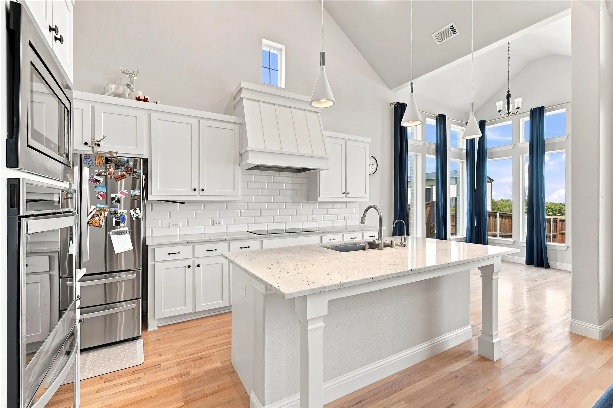 Kitchen featuring a central island with a light-toned countertop, white cabinetry with dark hardware, stainless steel appliances, and wood-finish flooring