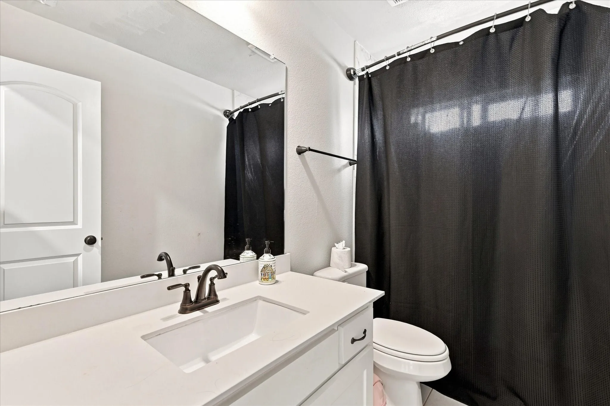 Vanity with integrated sink, bronze-finish faucet, and a large mirror