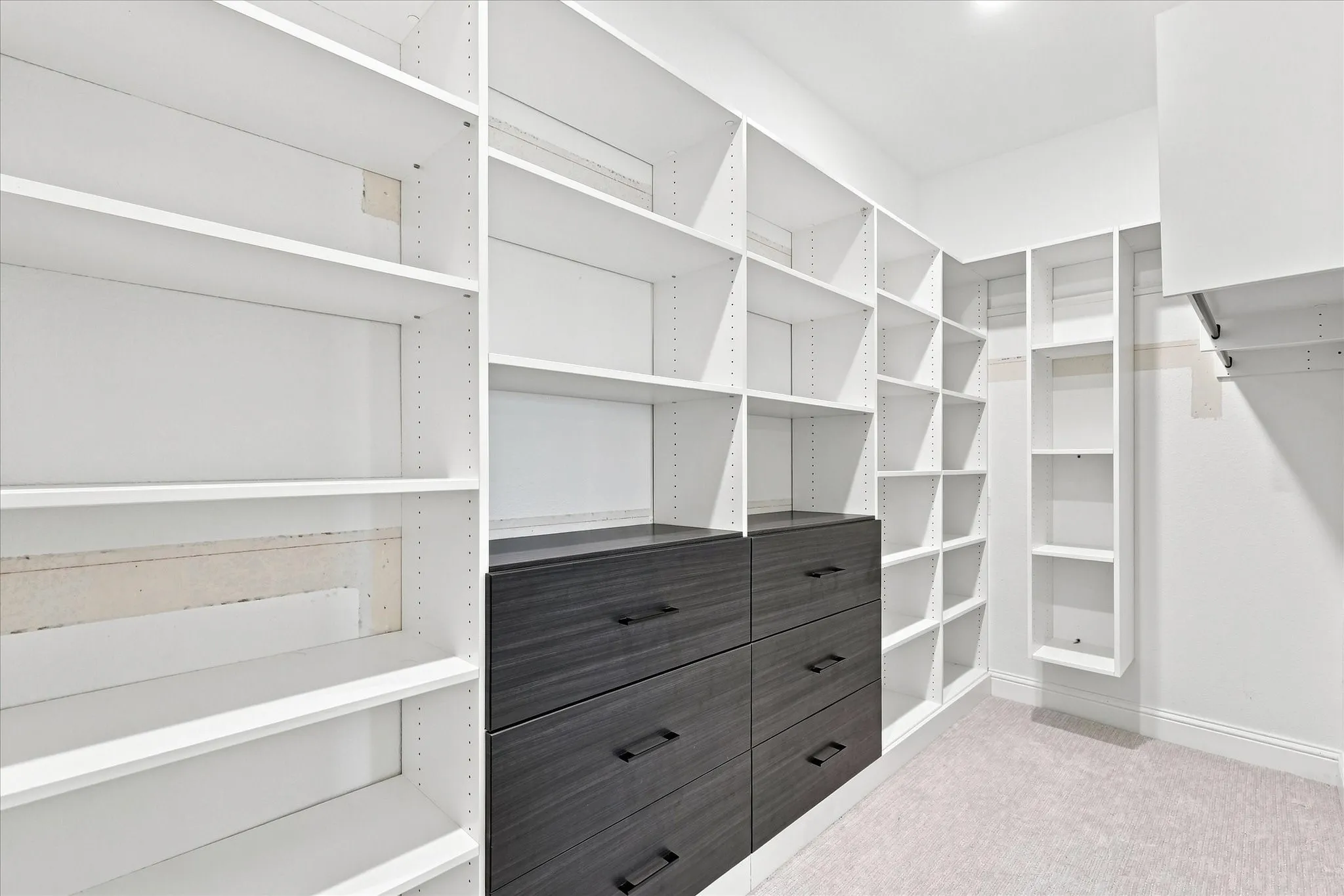 Built-in closet system with white shelving and dark wood-finish drawers