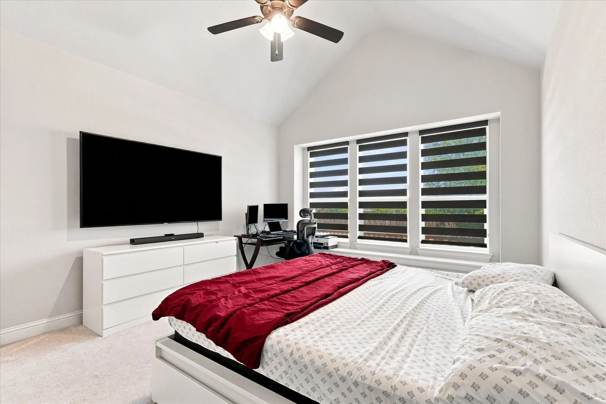 Vaulted ceiling with a ceiling fan, recessed window with horizontal blinds, and carpeted flooring