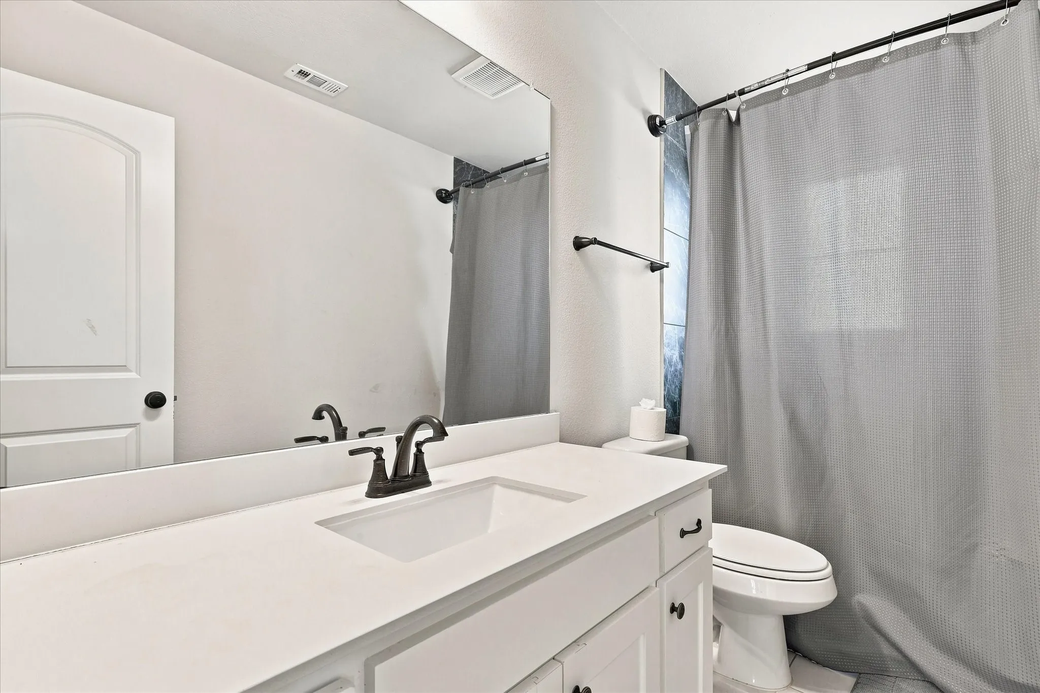 White vanity with integrated sink, bronze-finish faucet, and coordinating hardware