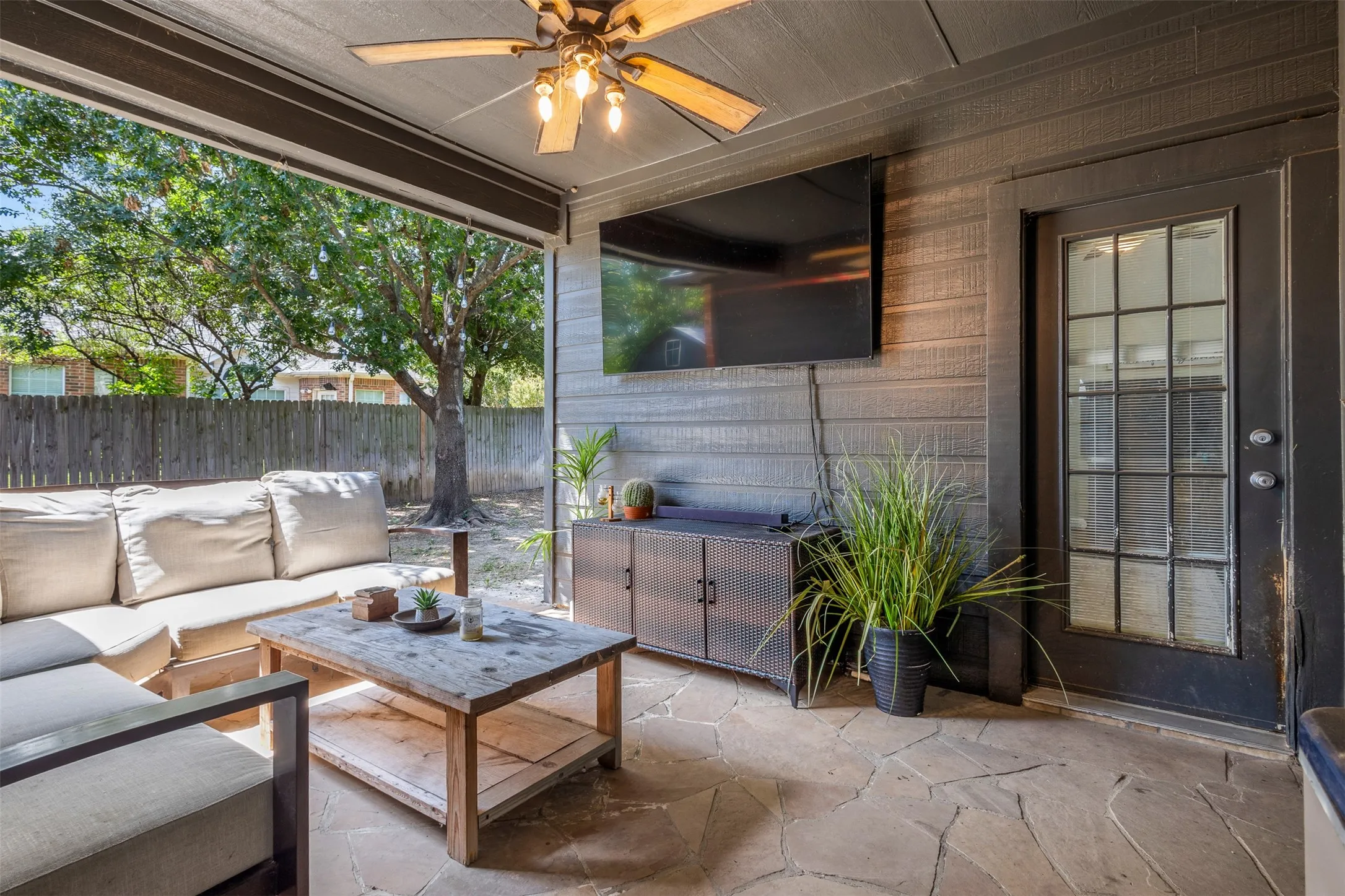 Covered patio featuring flagstone flooring, wood-paneled walls, and a ceiling fan