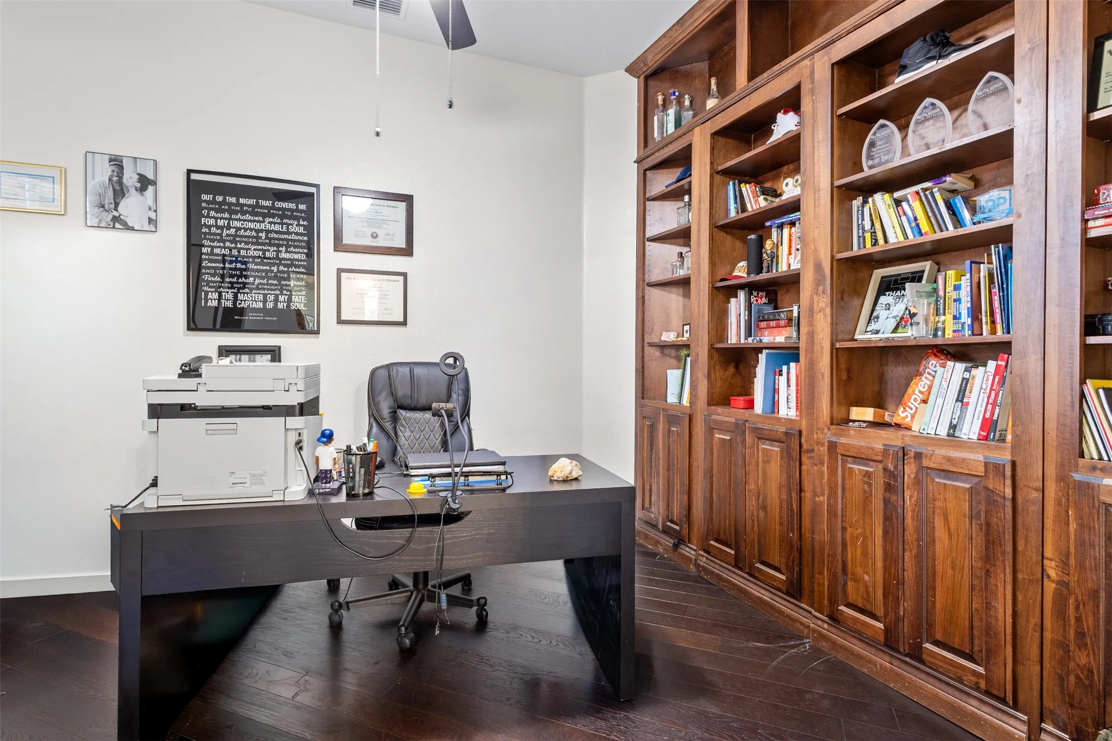 Room featuring dark wood-finish flooring, white walls, and built-in wood cabinetry with integrated shelving
