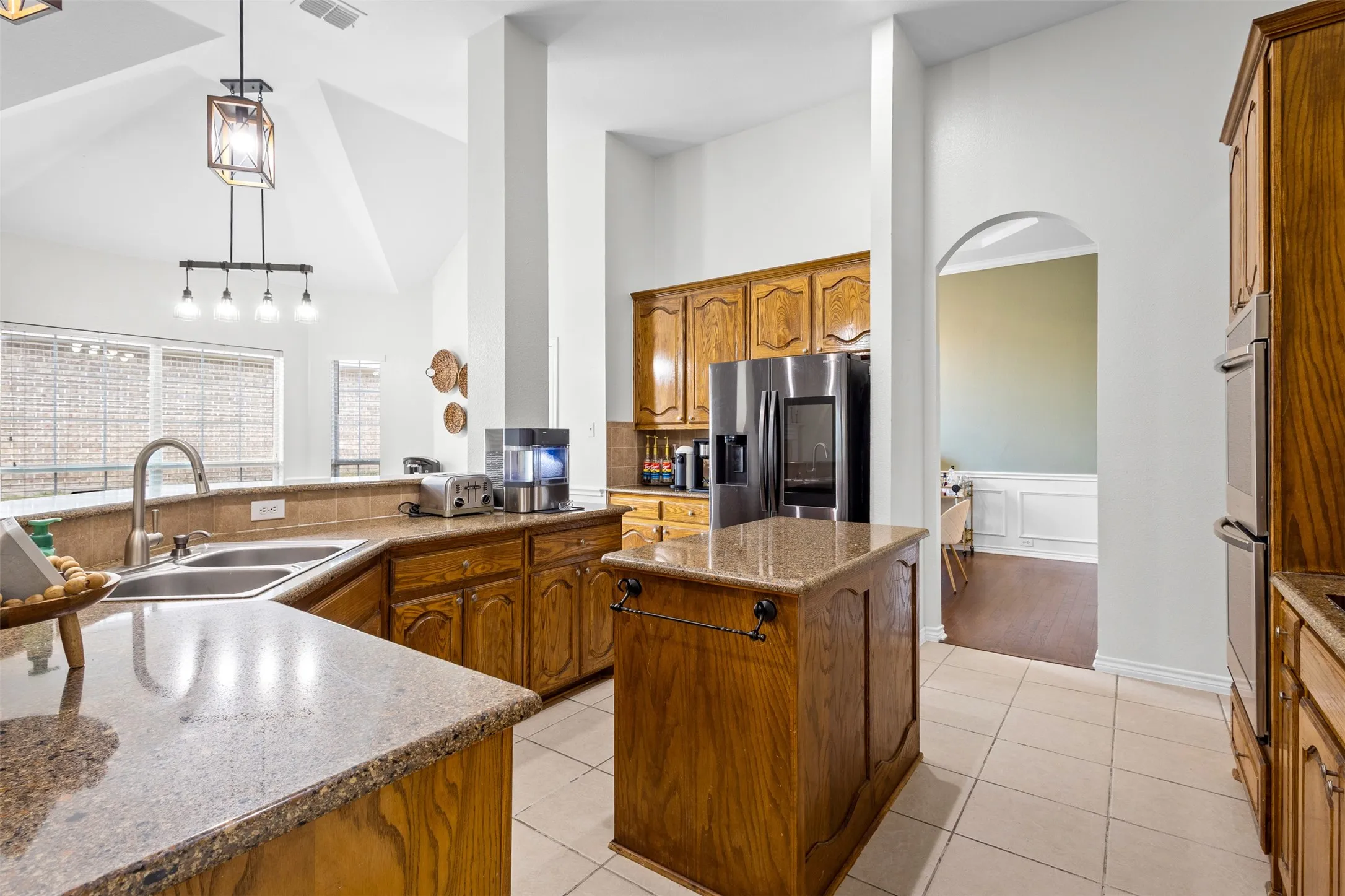 Kitchen featuring wood cabinetry, granite countertops, stainless steel refrigerator, and ceramic tile flooring