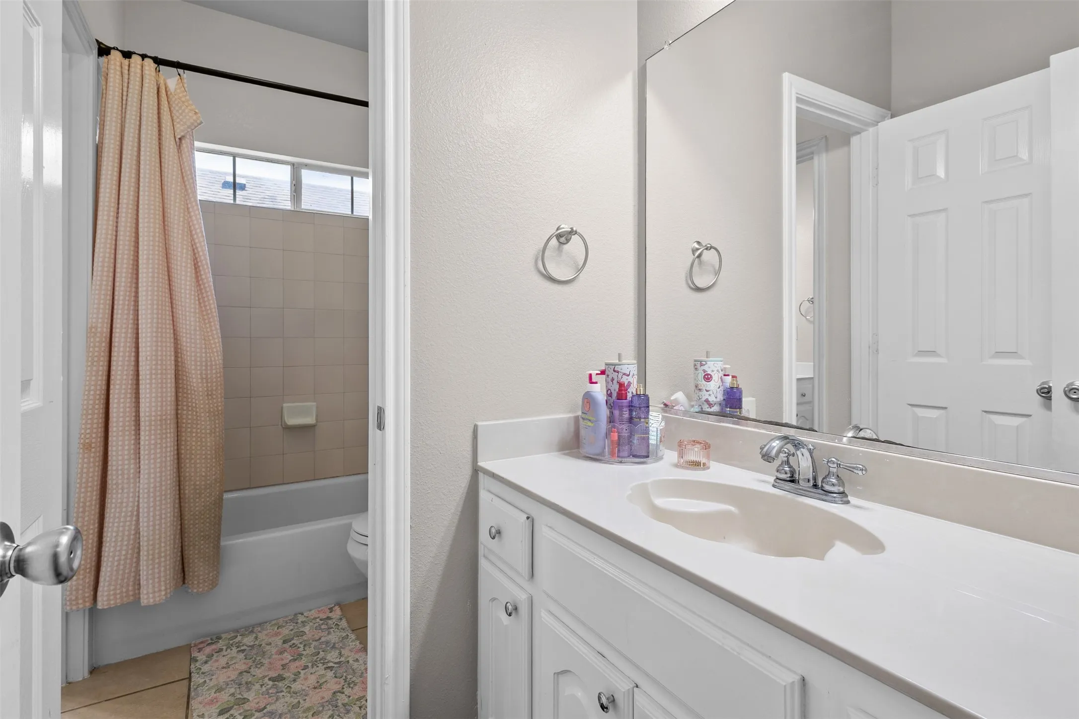 White vanity with integrated sink, chrome faucet, and expansive wall-mounted mirror