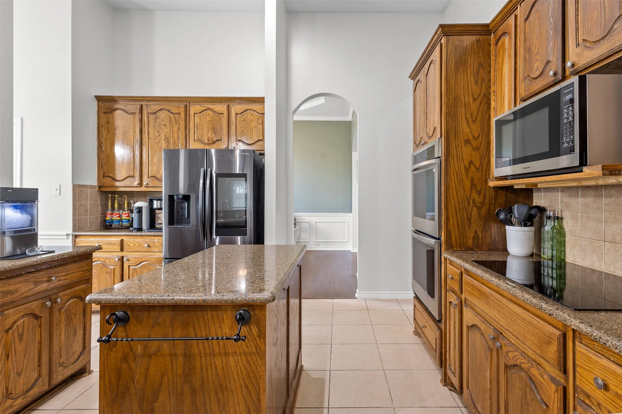Kitchen featuring wood cabinetry, stainless steel appliances, granite countertops, and tile flooring