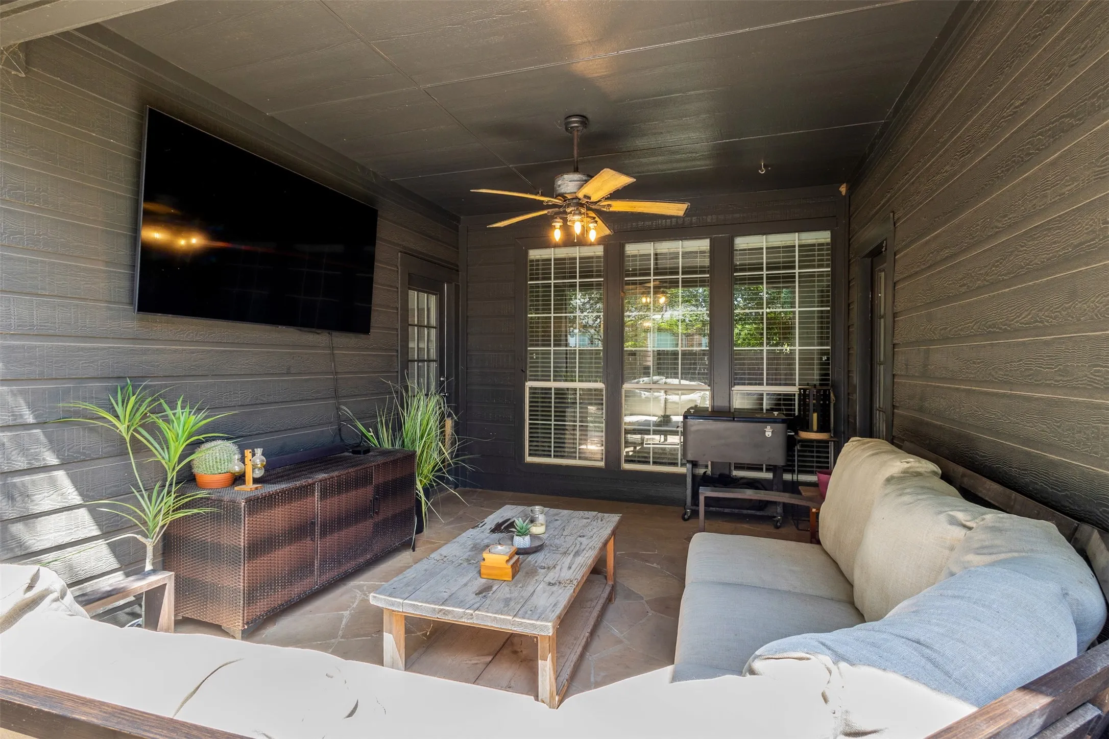 Covered patio featuring flagstone flooring, wood-paneled walls, and a ceiling fan