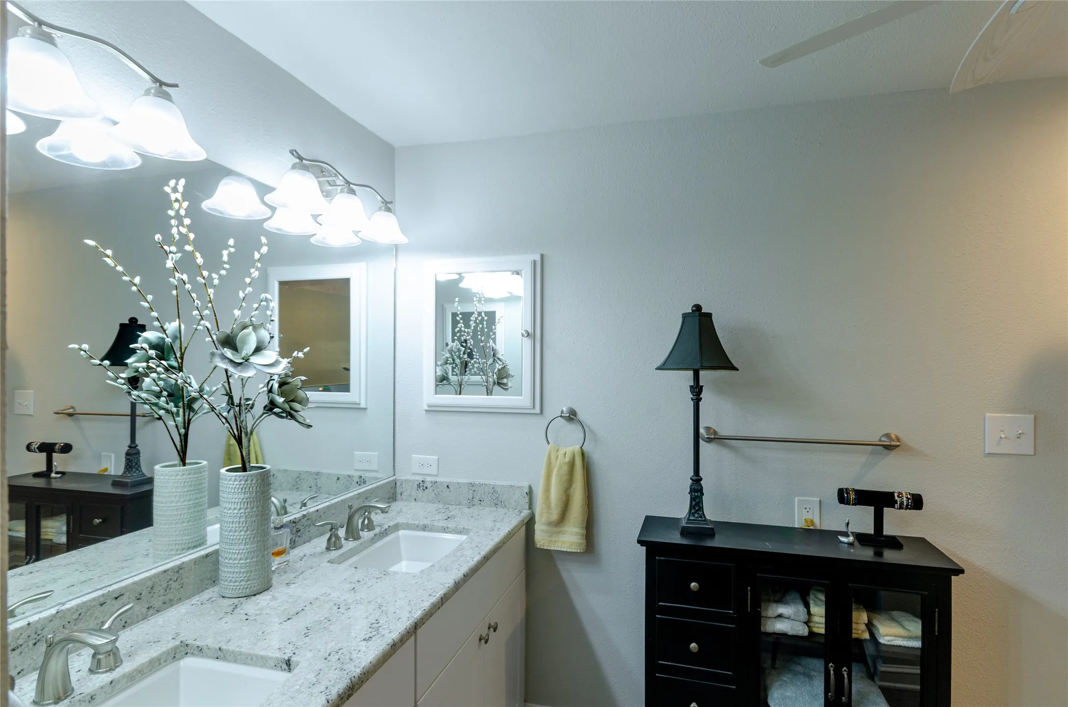 Dual vanity with integrated sinks, light-toned countertop, large wall-mounted mirror, and overhead vanity lighting