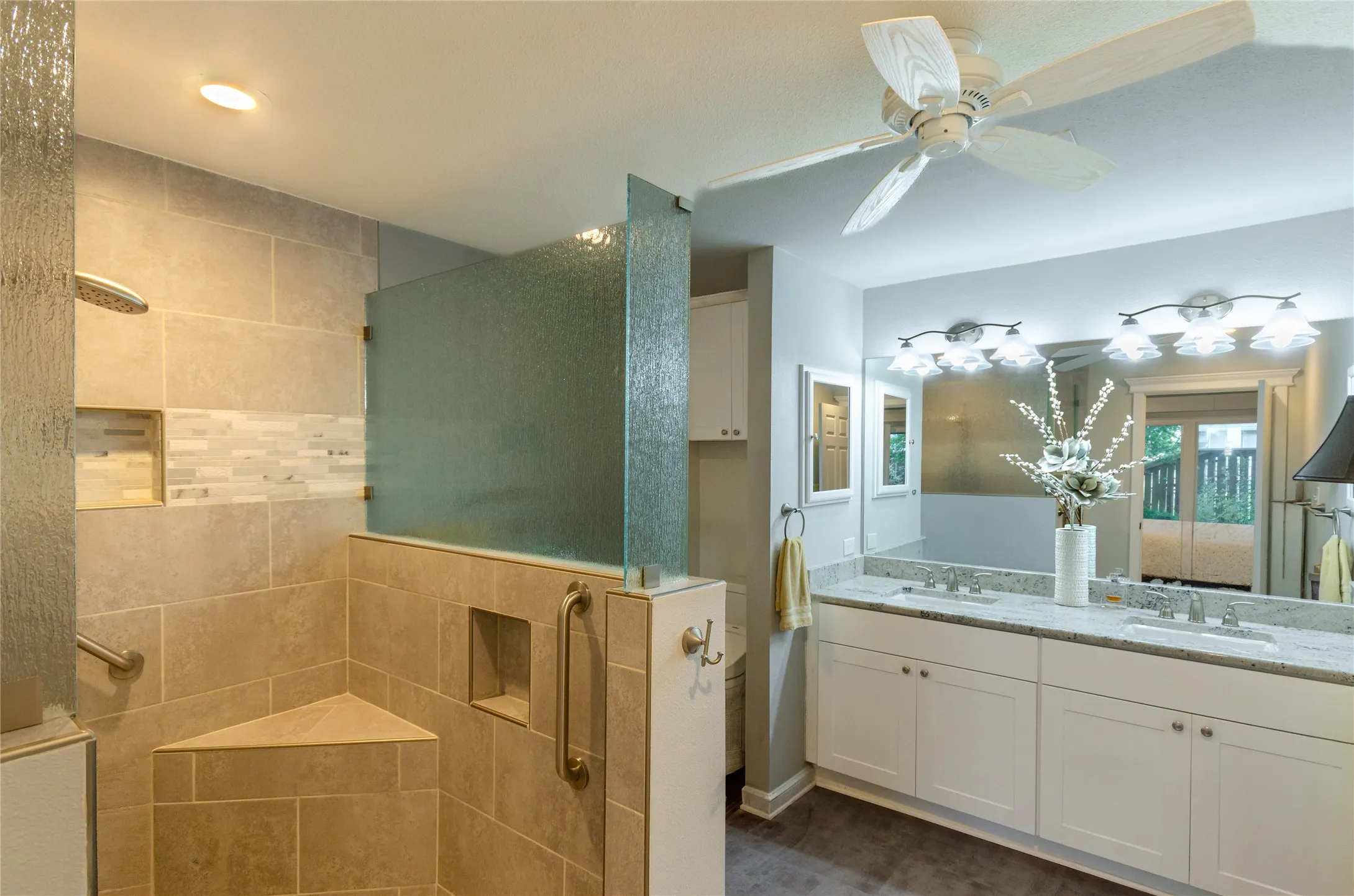 Tiled walk-in shower with a built-in bench, dual shower heads, and an accent tile band