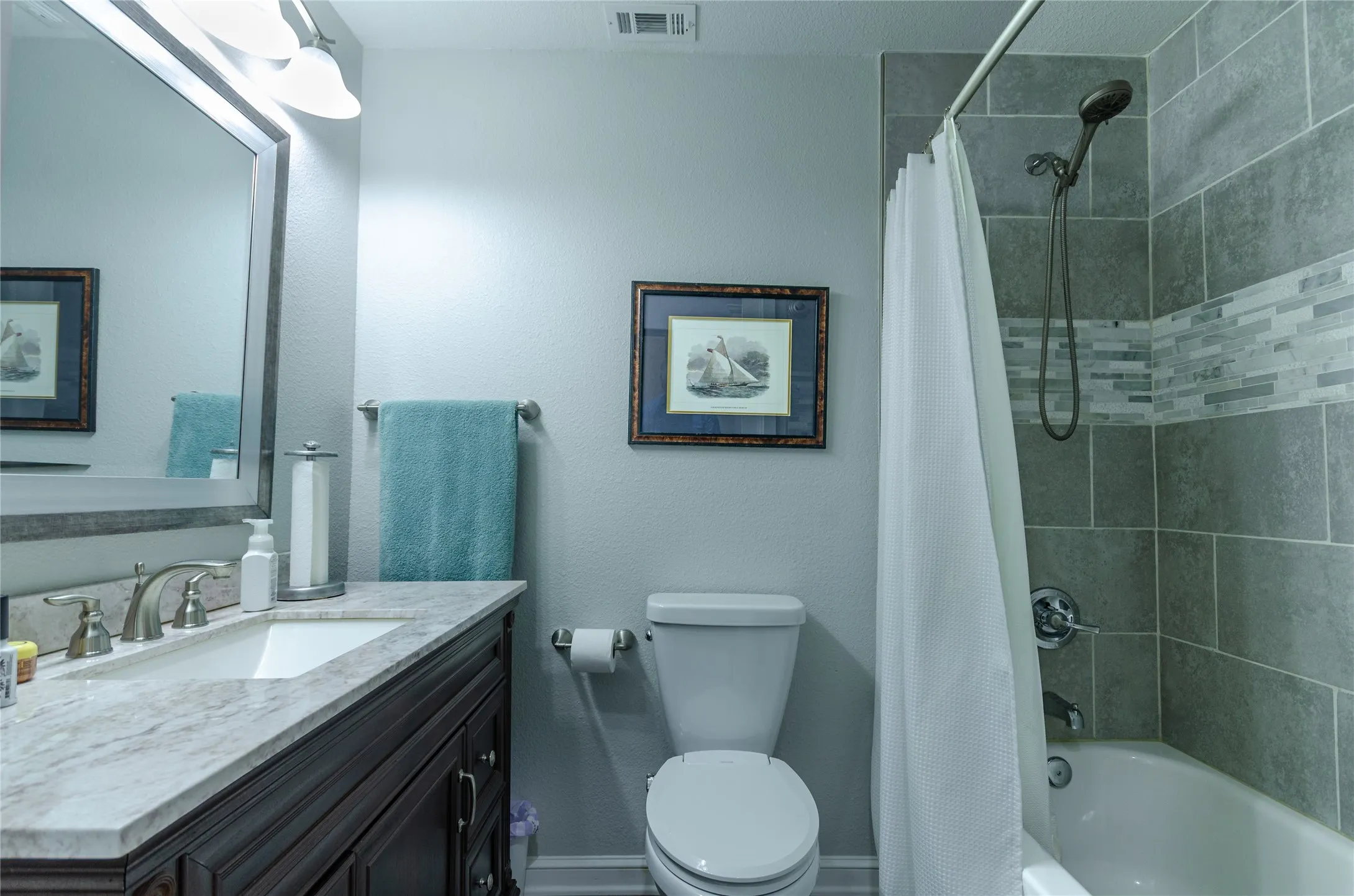 Bathroom featuring a dark wood-finish vanity with a light countertop, undermount sink, and brushed nickel fixtures