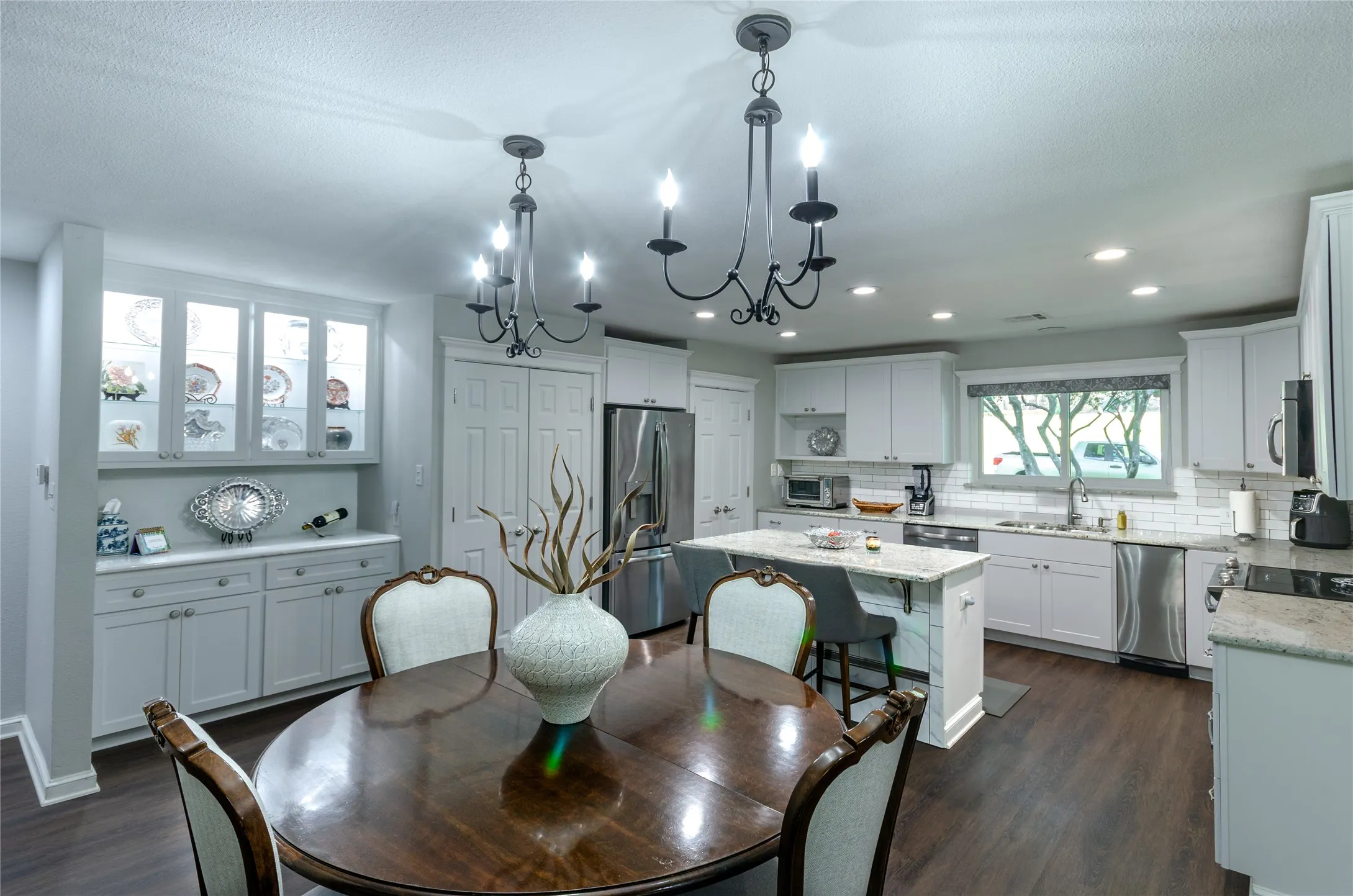 Kitchen with white cabinetry, stainless steel appliances, a center island with seating, and wood-finish flooring
