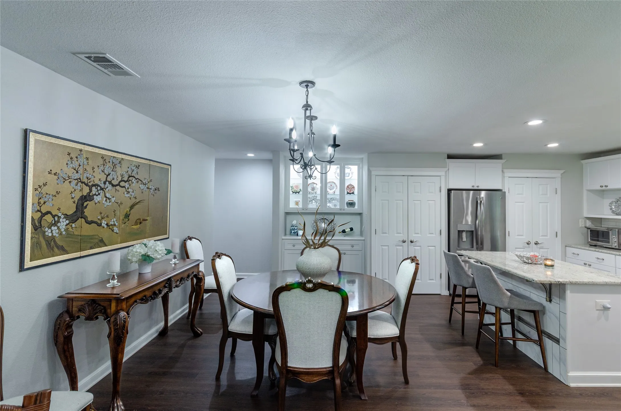 Open-concept dining area with wood-finish flooring, a built-in display cabinet, and recessed lighting