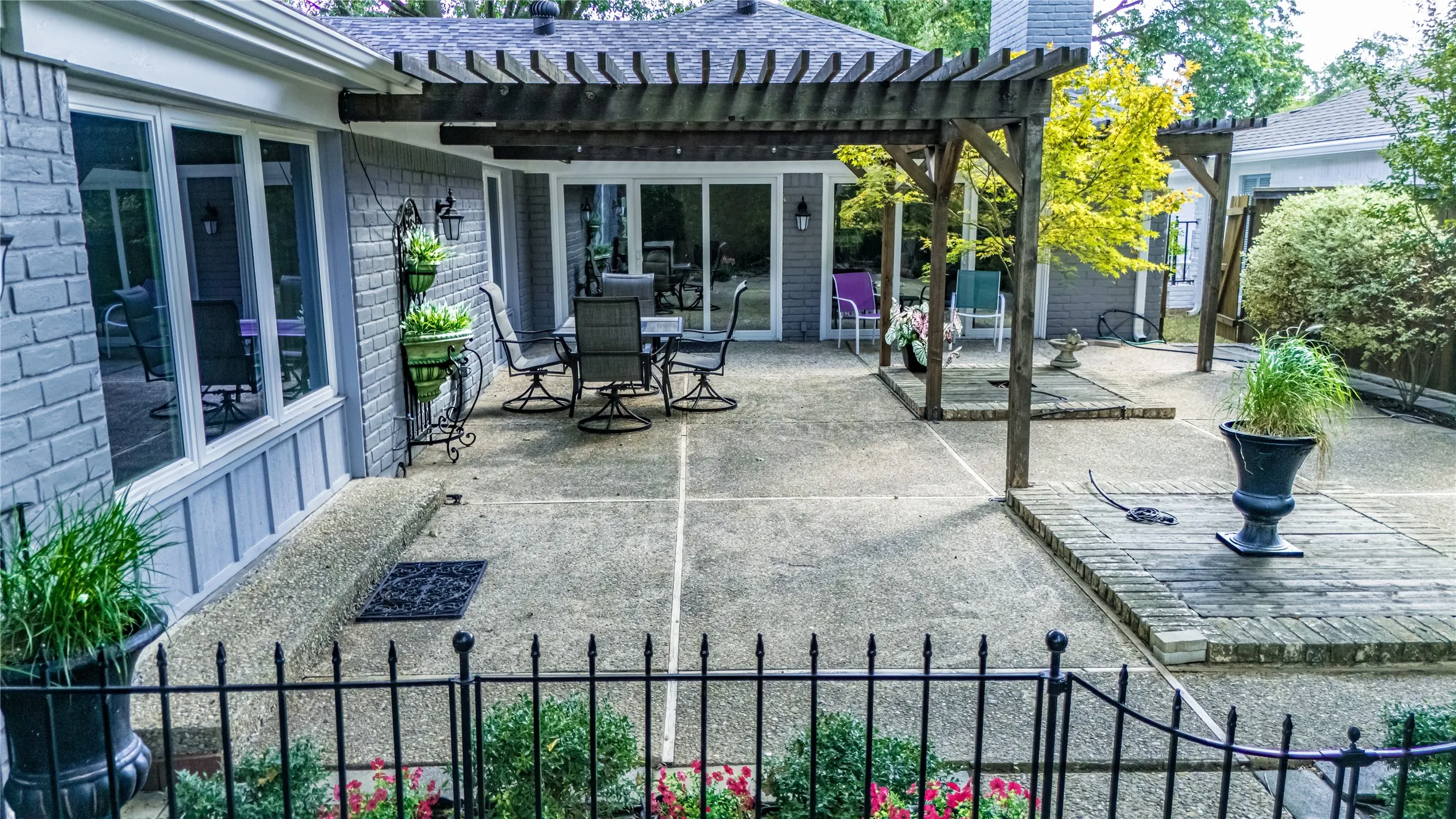 Expansive concrete patio featuring a wood pergola and brick paver accents