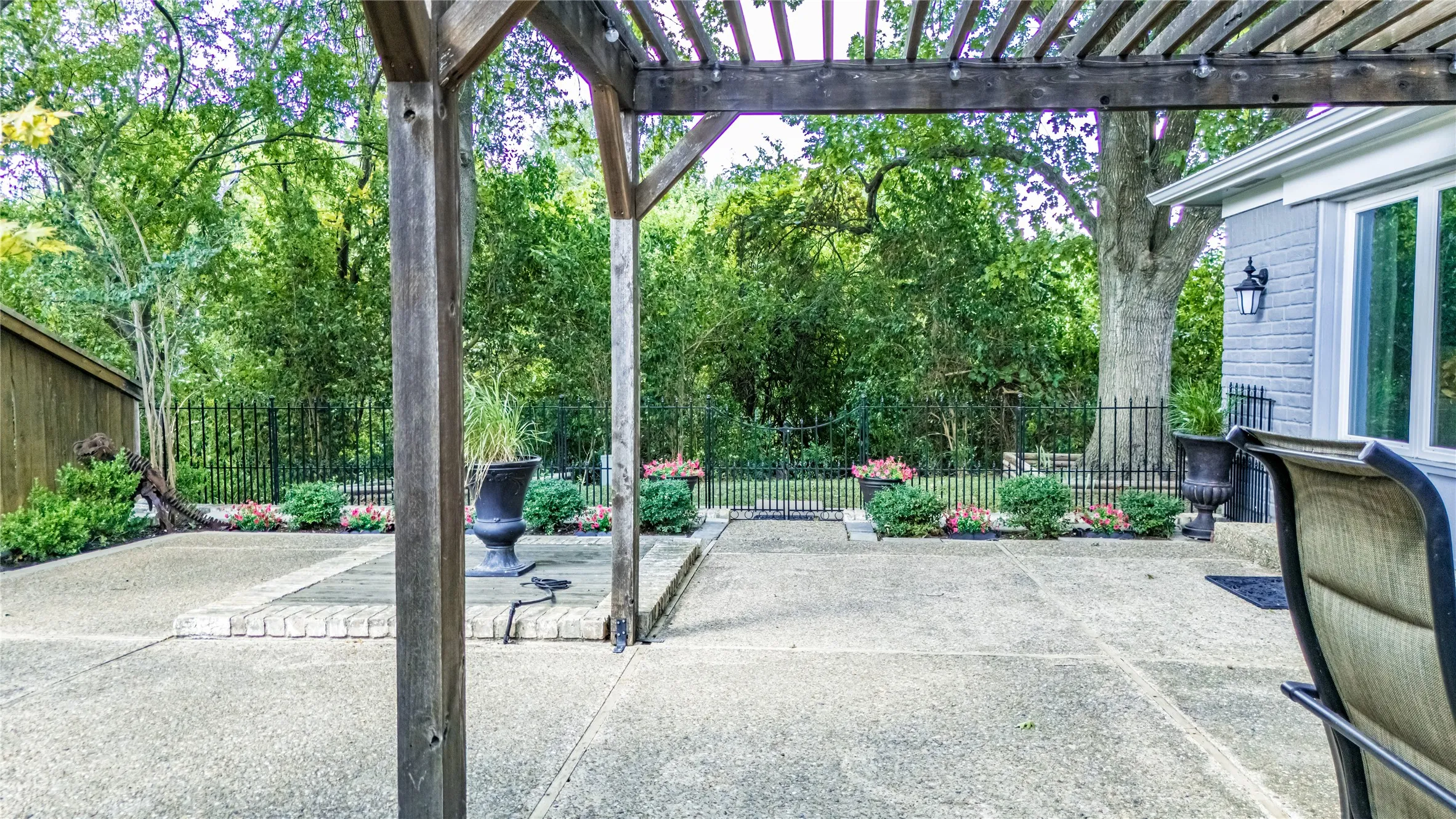 Patio with a wood pergola, concrete surface, and surrounding landscaping