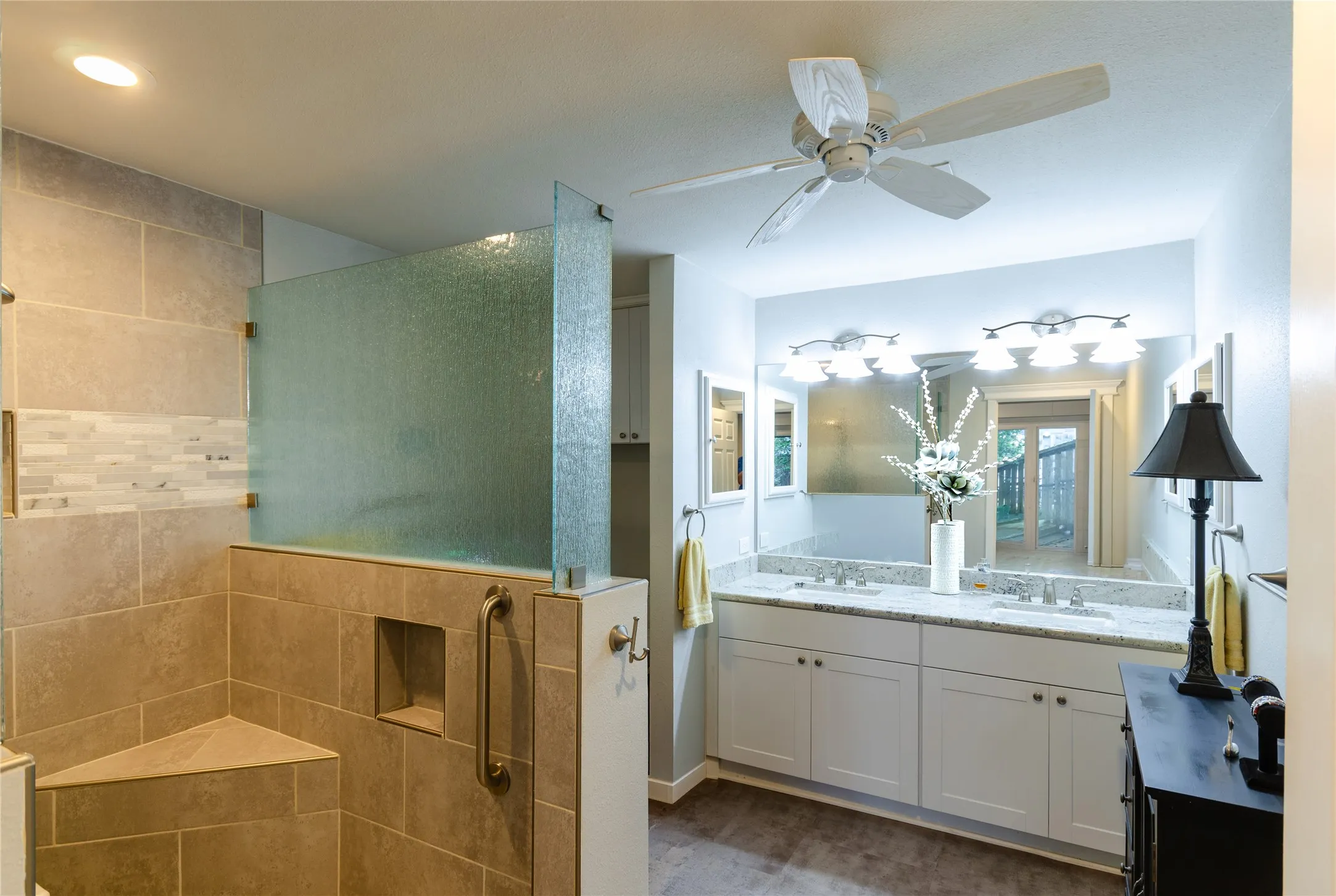 Walk-in shower with textured glass partition and integrated bench