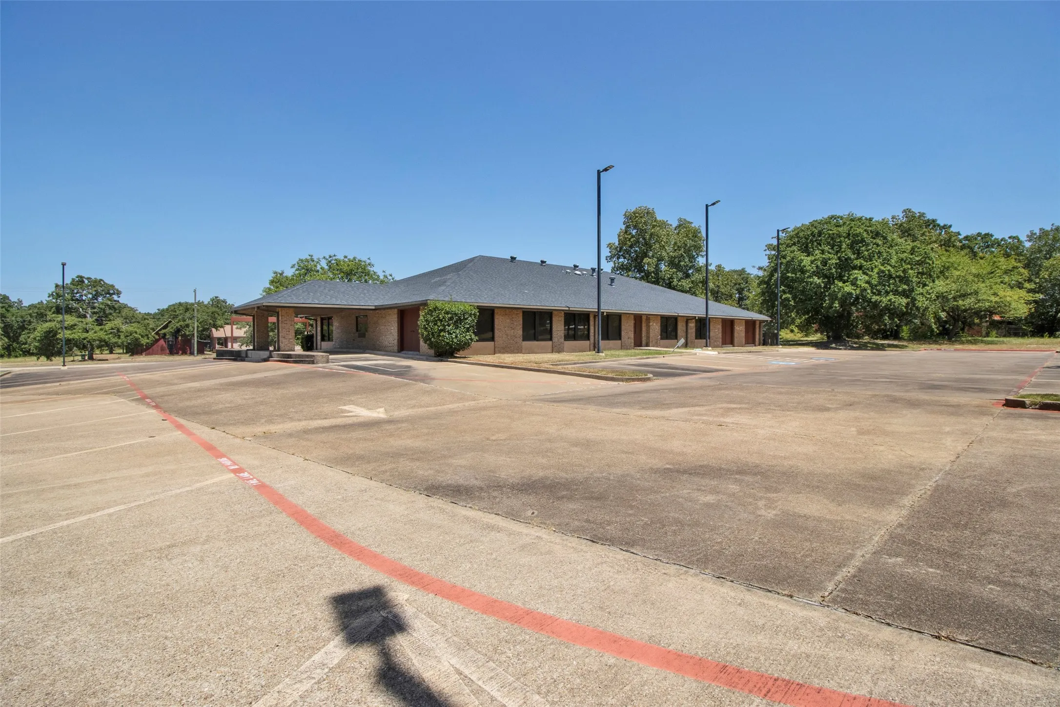 Expansive concrete parking lot with a brick exterior building and dark roof