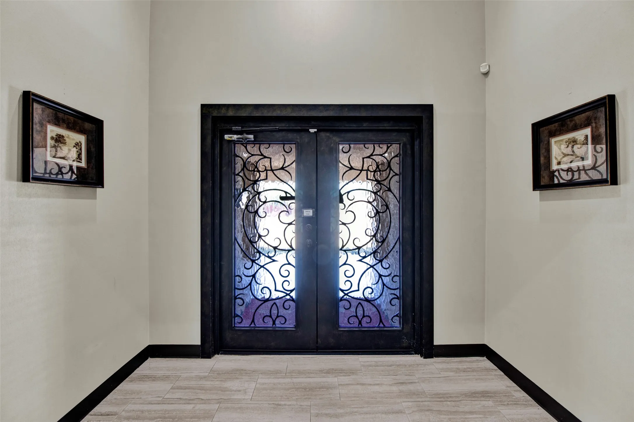Ornate double entry doors with decorative ironwork, framed by a dark trim