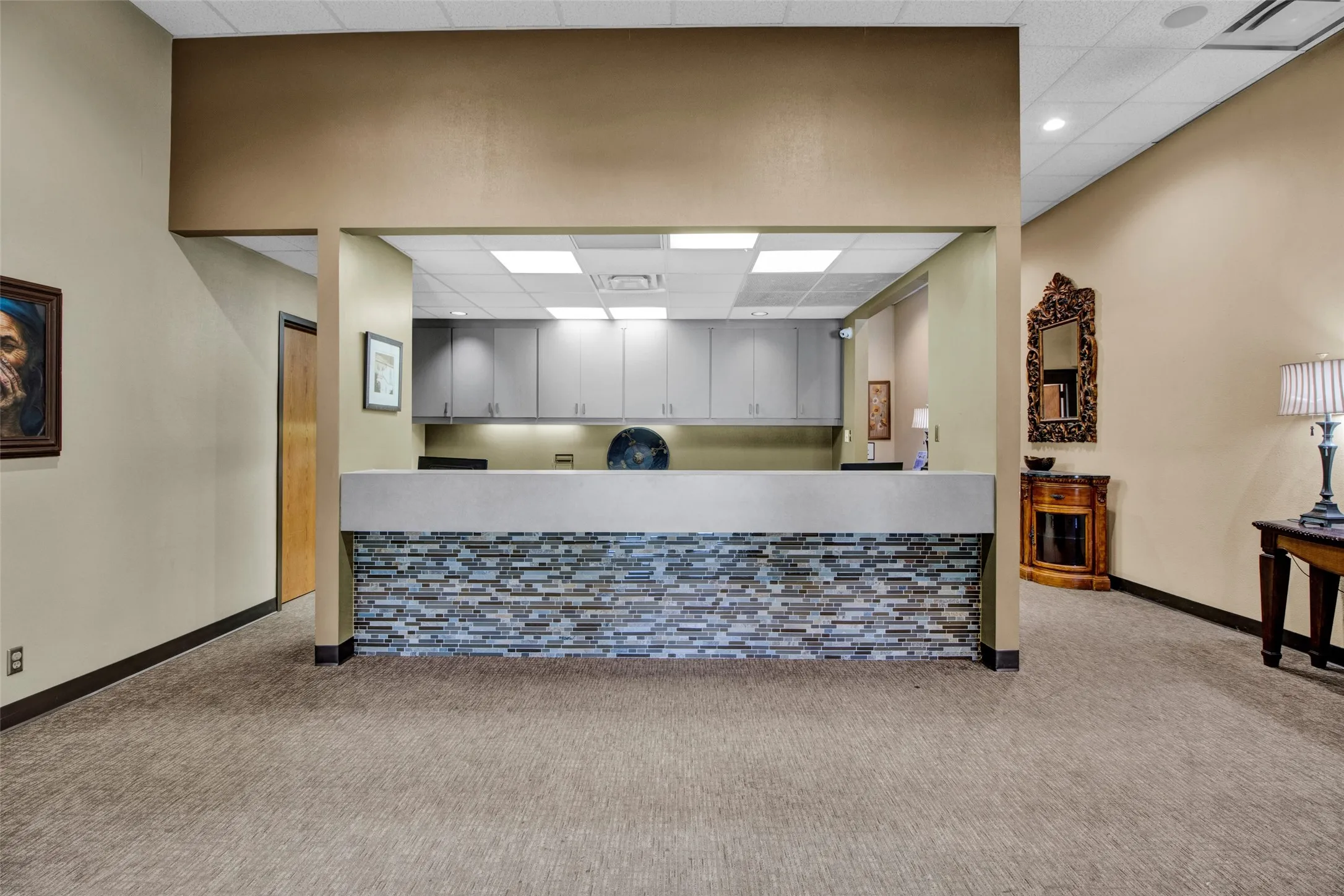 Reception counter with a stacked stone facade, recessed lighting, and wall-mounted cabinetry