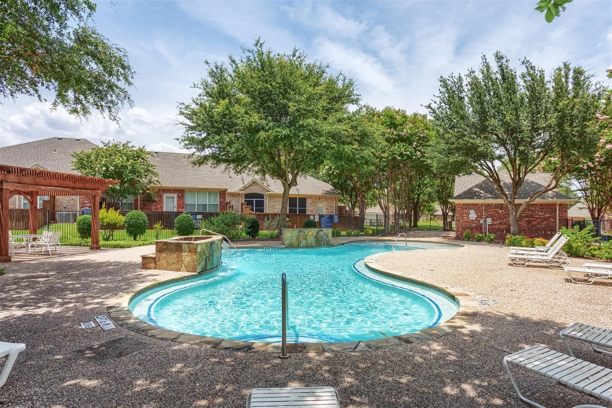 Resort-style resort pool featuring a curved design with sun loungers and mature landscaping