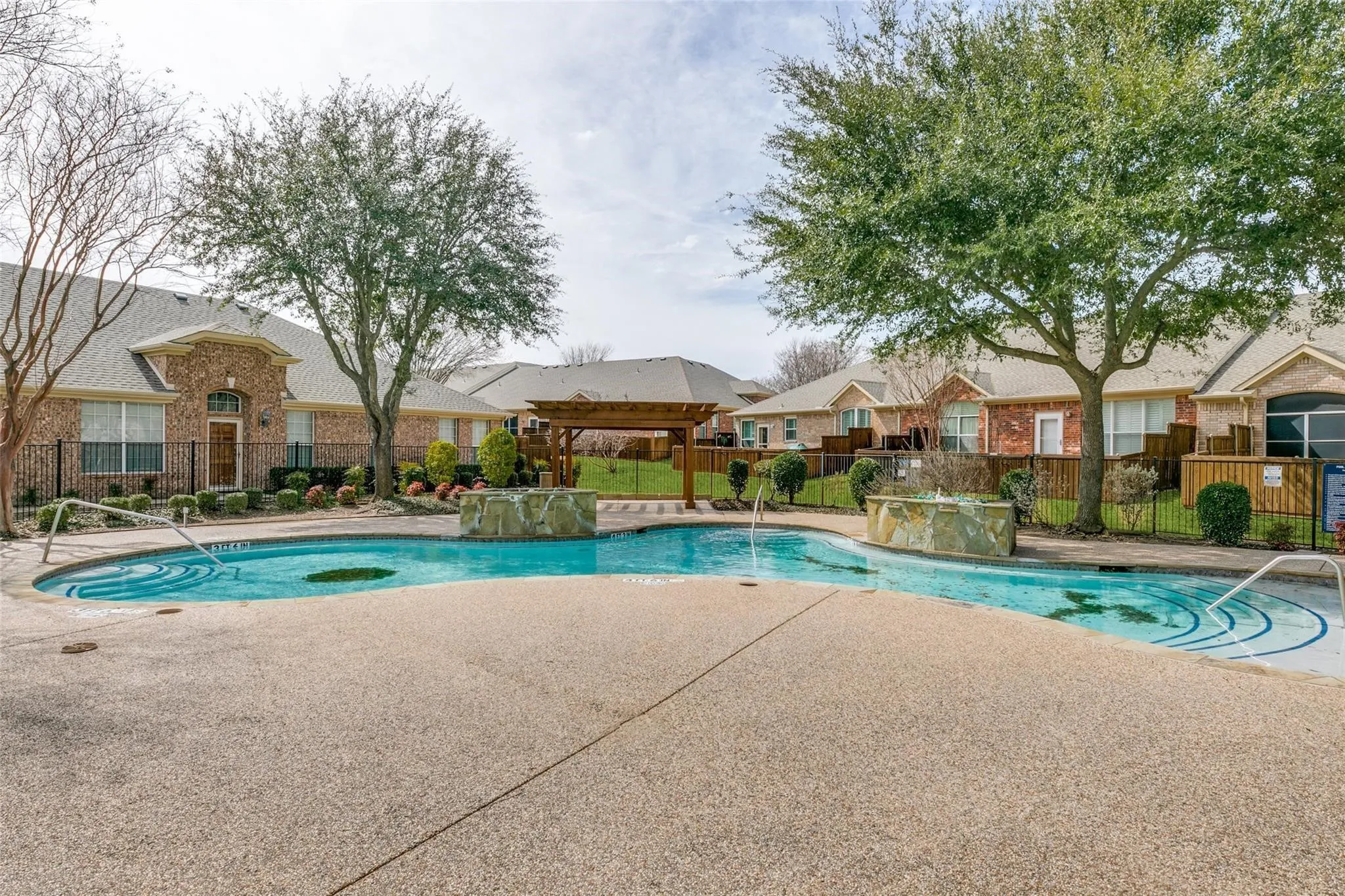 Resort-style pool with integrated water features and textured decking