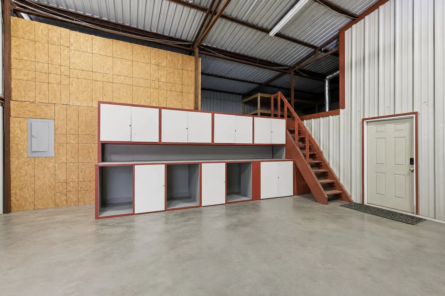 Spacious storage or warehouse with cabinetry and upstairs loft for additional storage. There is another AC-cooled room for storage not pictured  (contents have been removed using AI)