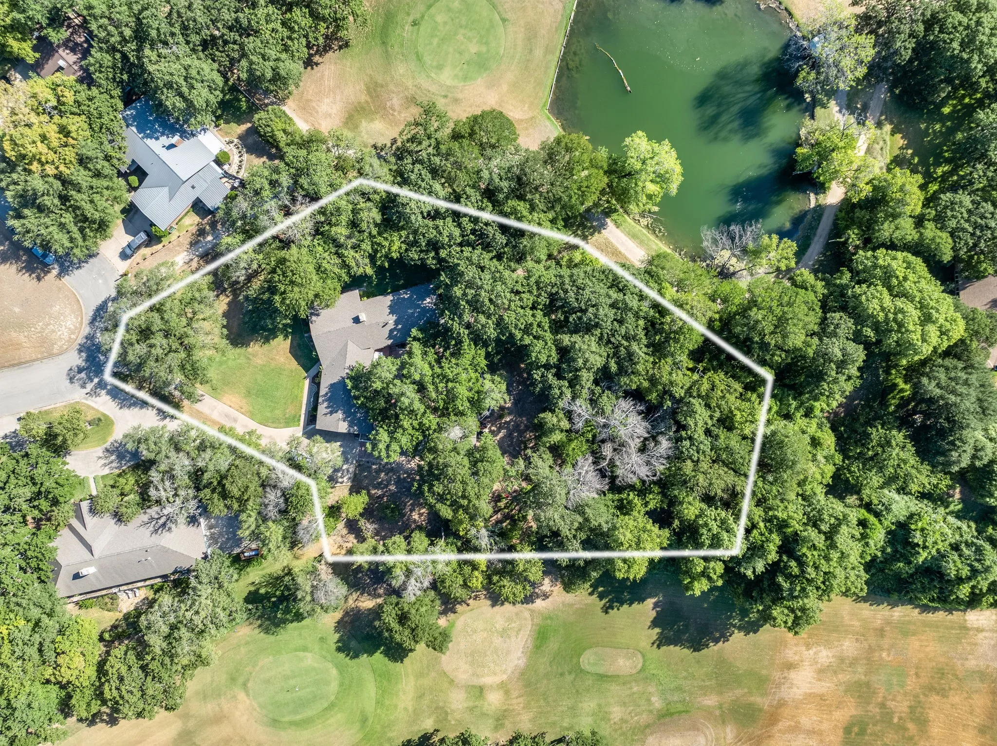 Property featuring a mature tree canopy, golf course frontage, and a water feature