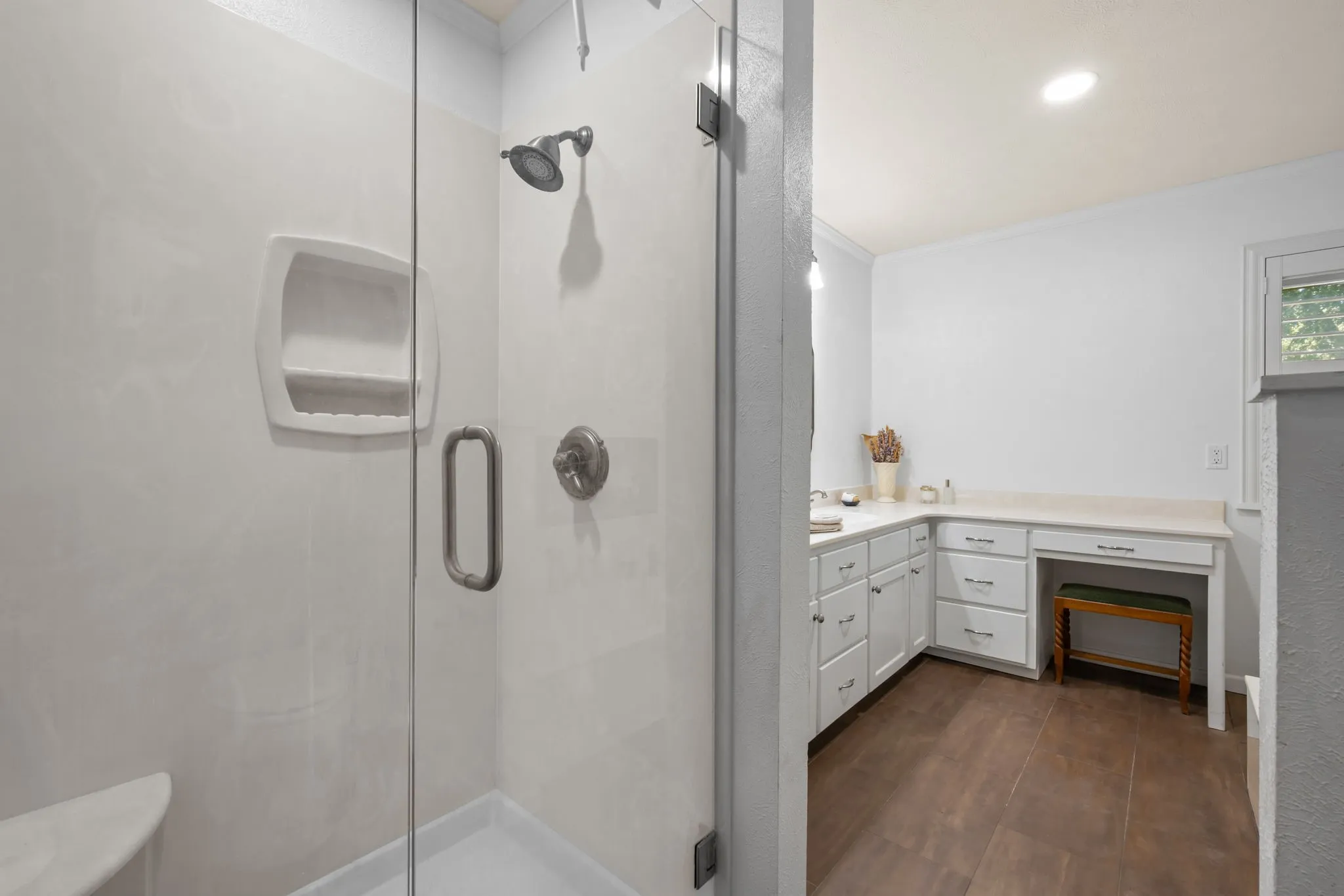 Glass-enclosed shower with a built-in soap dish and corner shelf