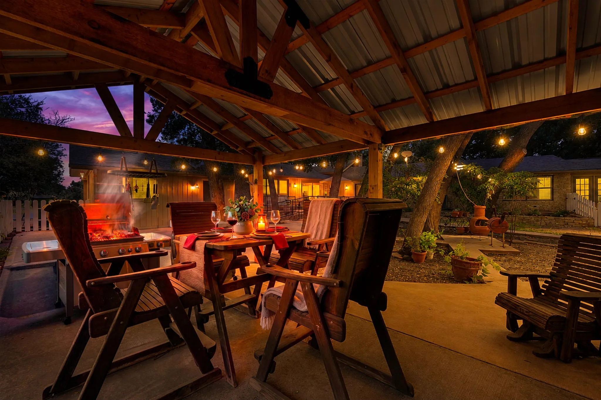 Expansive covered patio featuring a corrugated metal roof, exposed wood beams, concrete flooring, and an outdoor grill area
