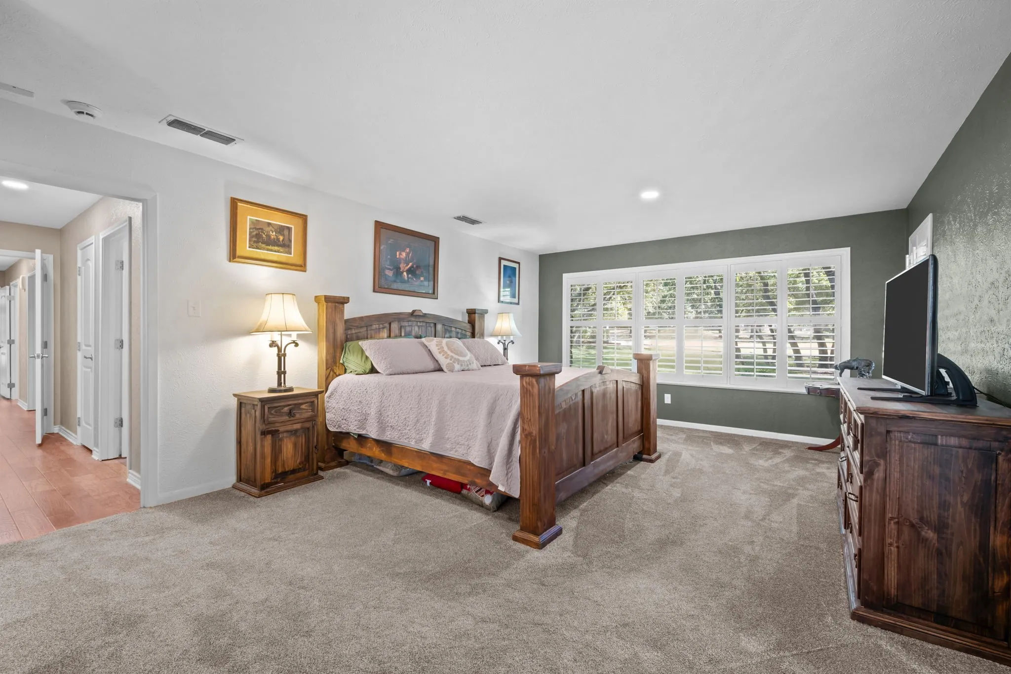 Wall-to-wall carpeting and a large window with plantation shutters