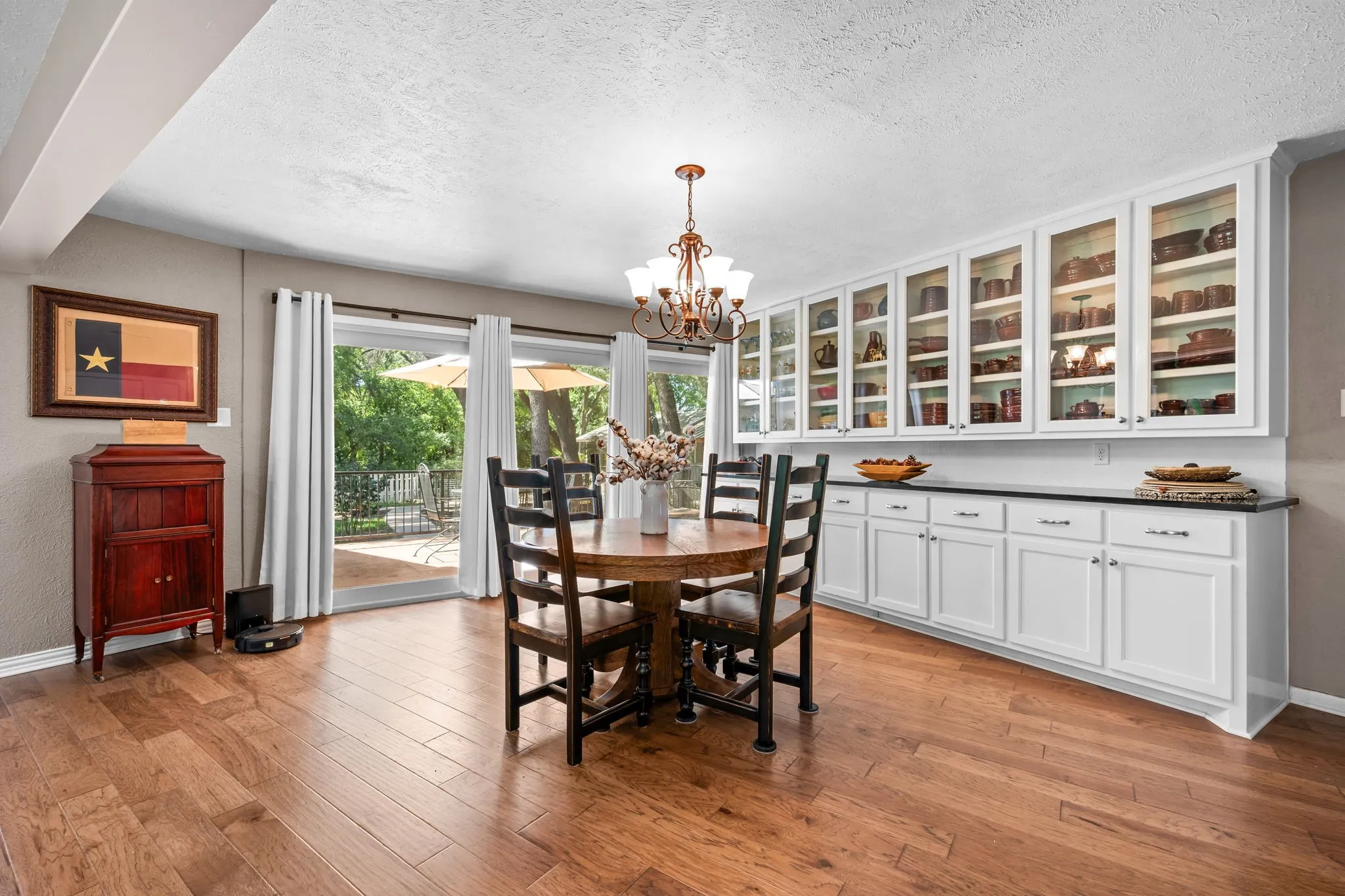 Wood-finish flooring, built-in white cabinetry with glass-front uppers, dark countertop, and sliding glass doors with direct outdoor access