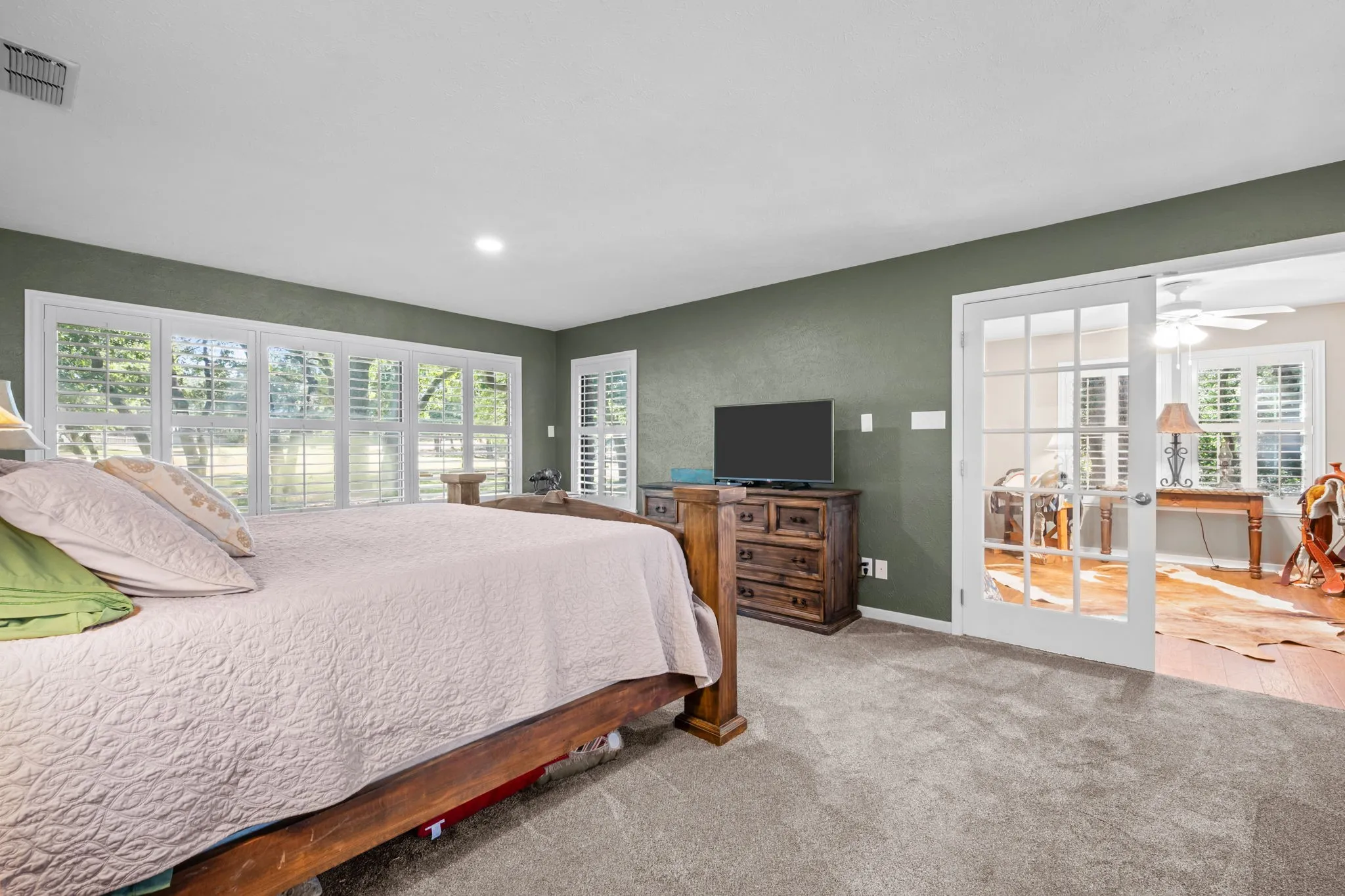 Wall-to-wall carpeting, recessed lighting, and a full wall of windows with plantation shutters