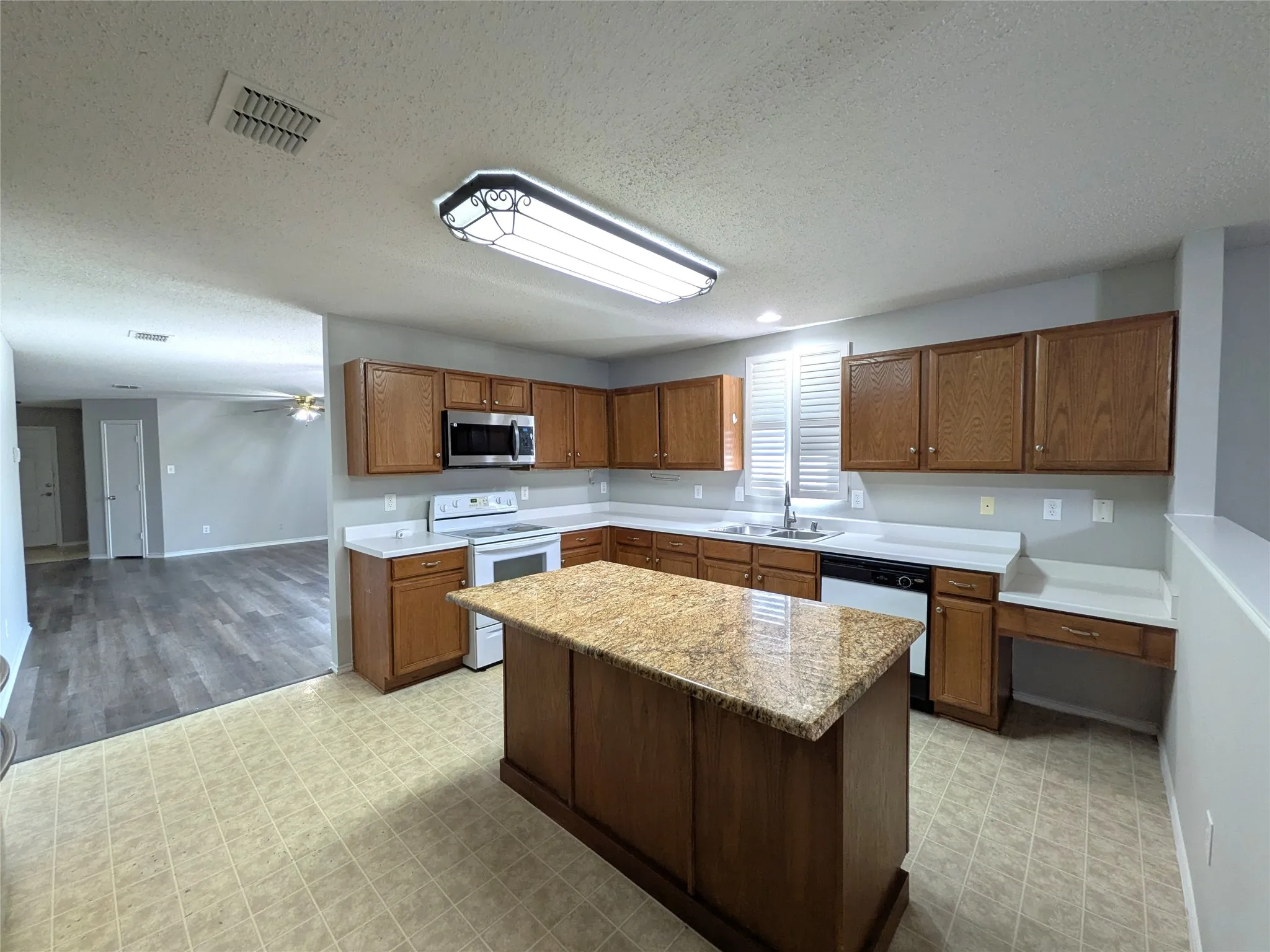 Kitchen featuring a granite-top island, wood cabinetry, white countertops, and tile flooring