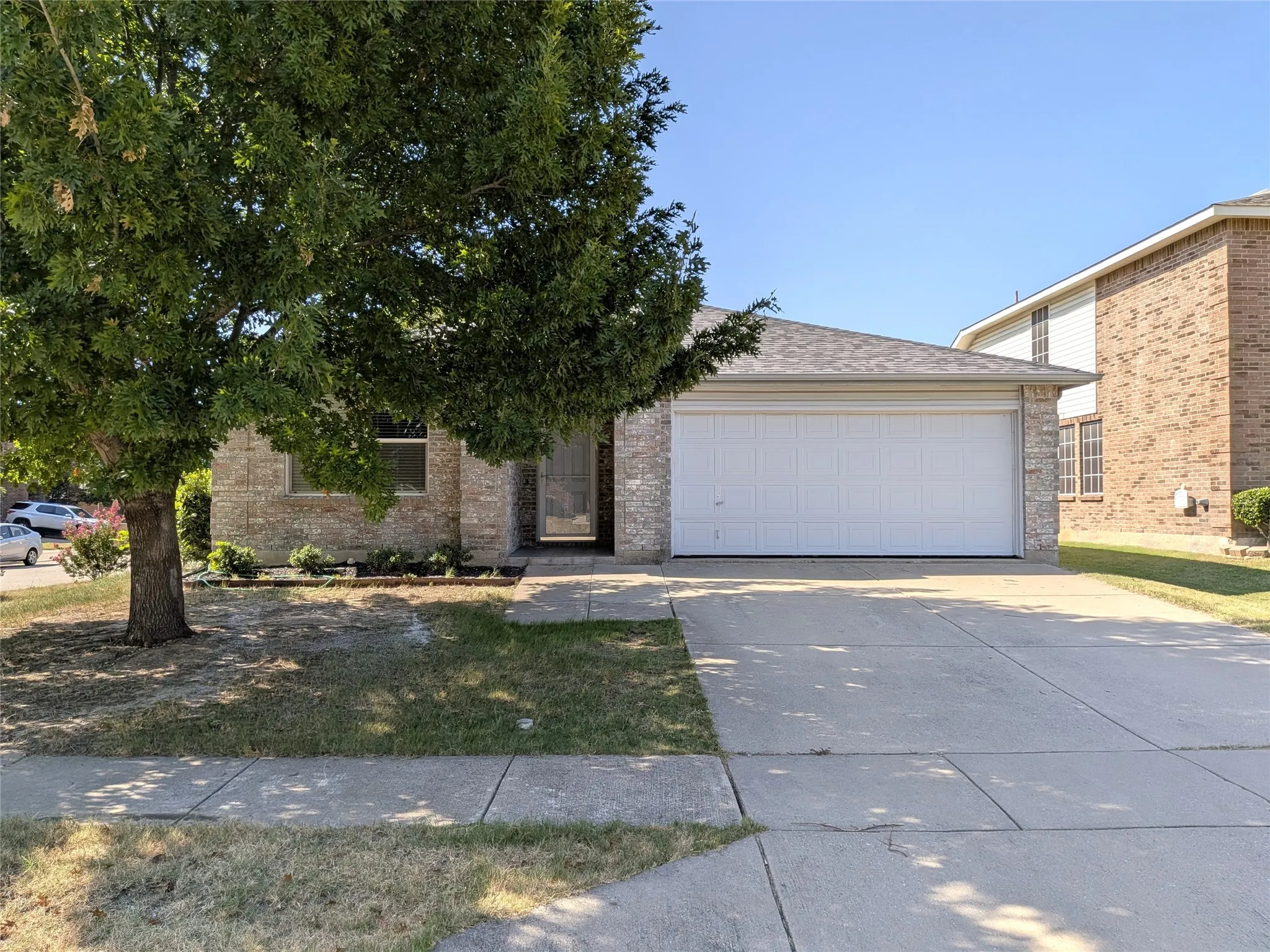 Single-story residence featuring a brick facade, attached two-car garage, and a concrete driveway