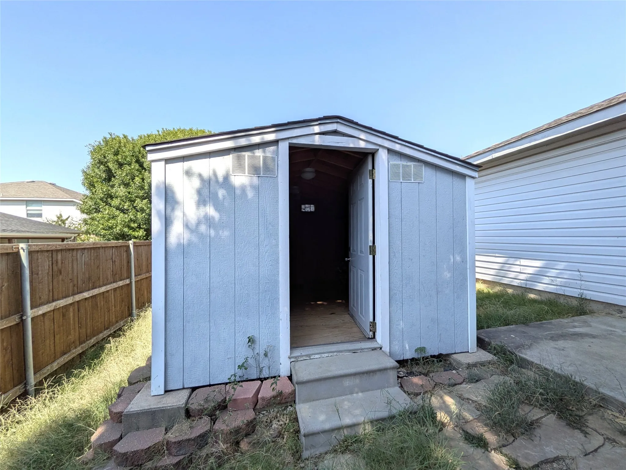 Utility shed featuring a gabled roof and a hinged door