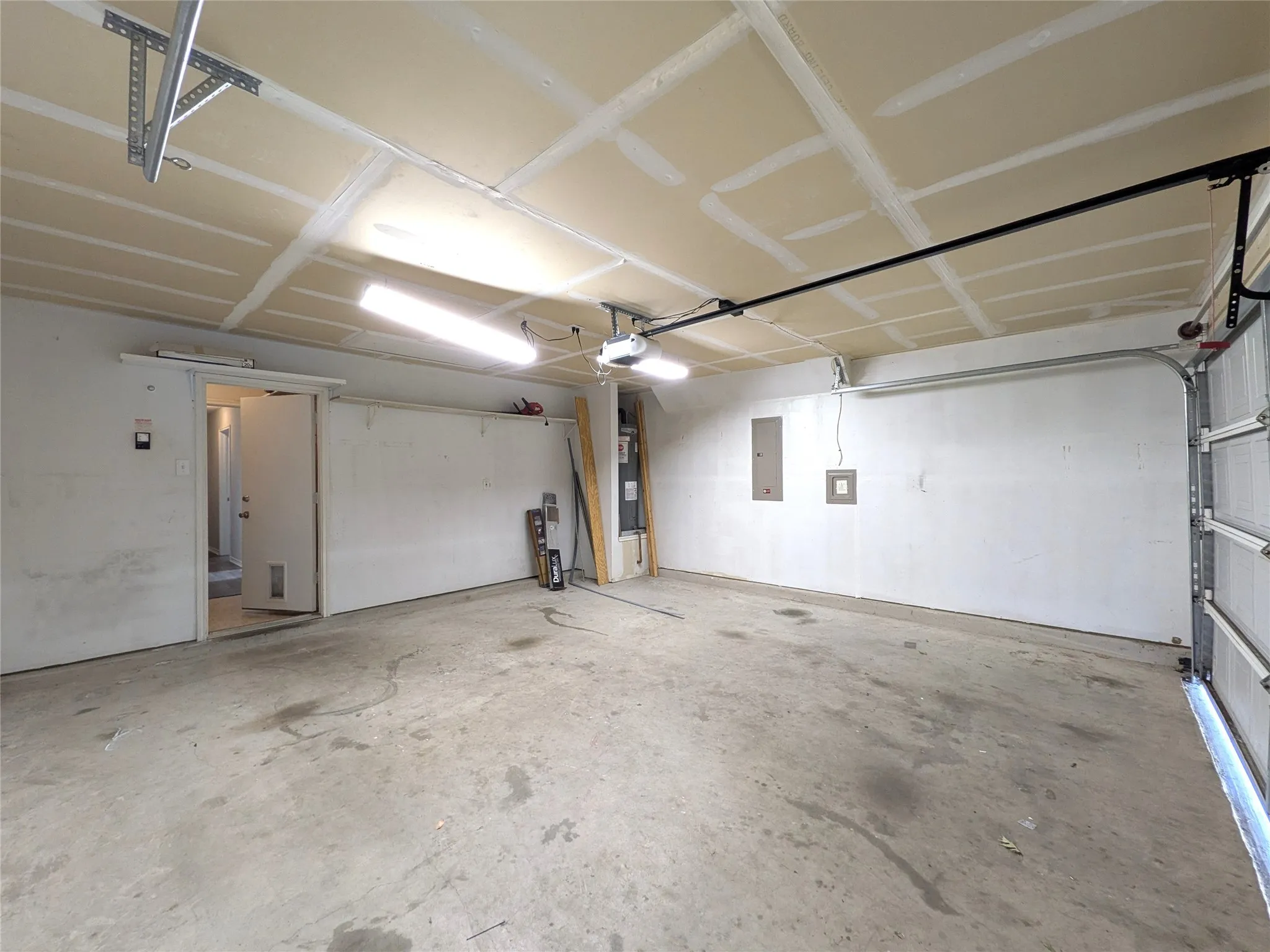 Spacious garage with concrete flooring, overhead lighting, and an automatic garage door opener