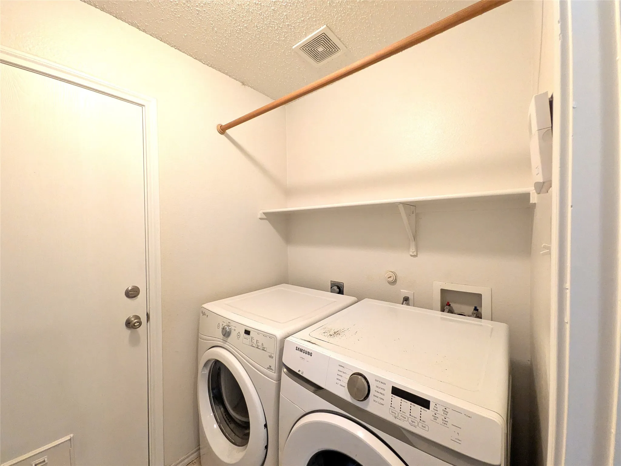 Dedicated laundry area featuring a wooden hanging rod, an overhead storage shelf, and a utility door