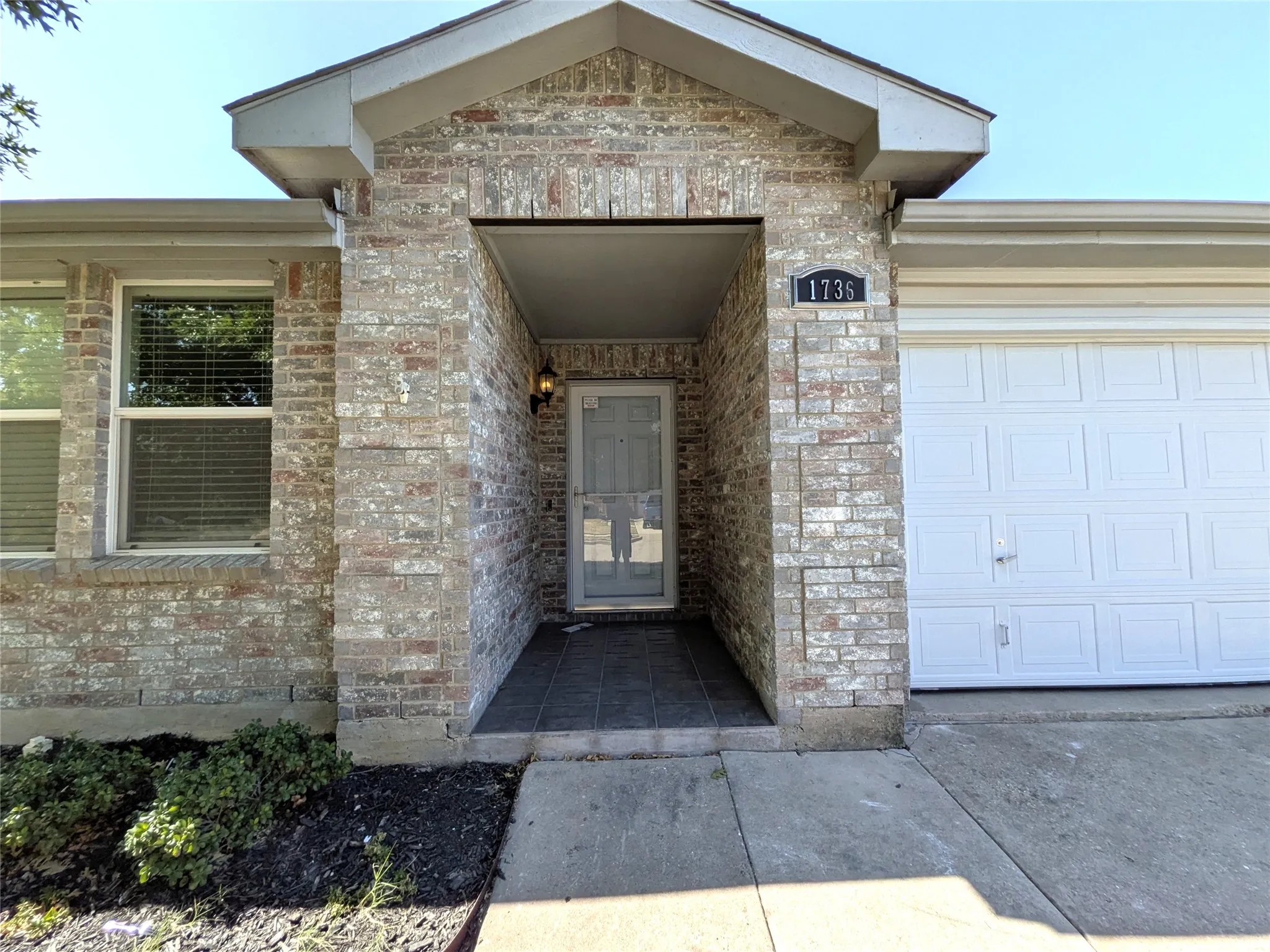 Brick exterior with an integrated garage and a covered entry