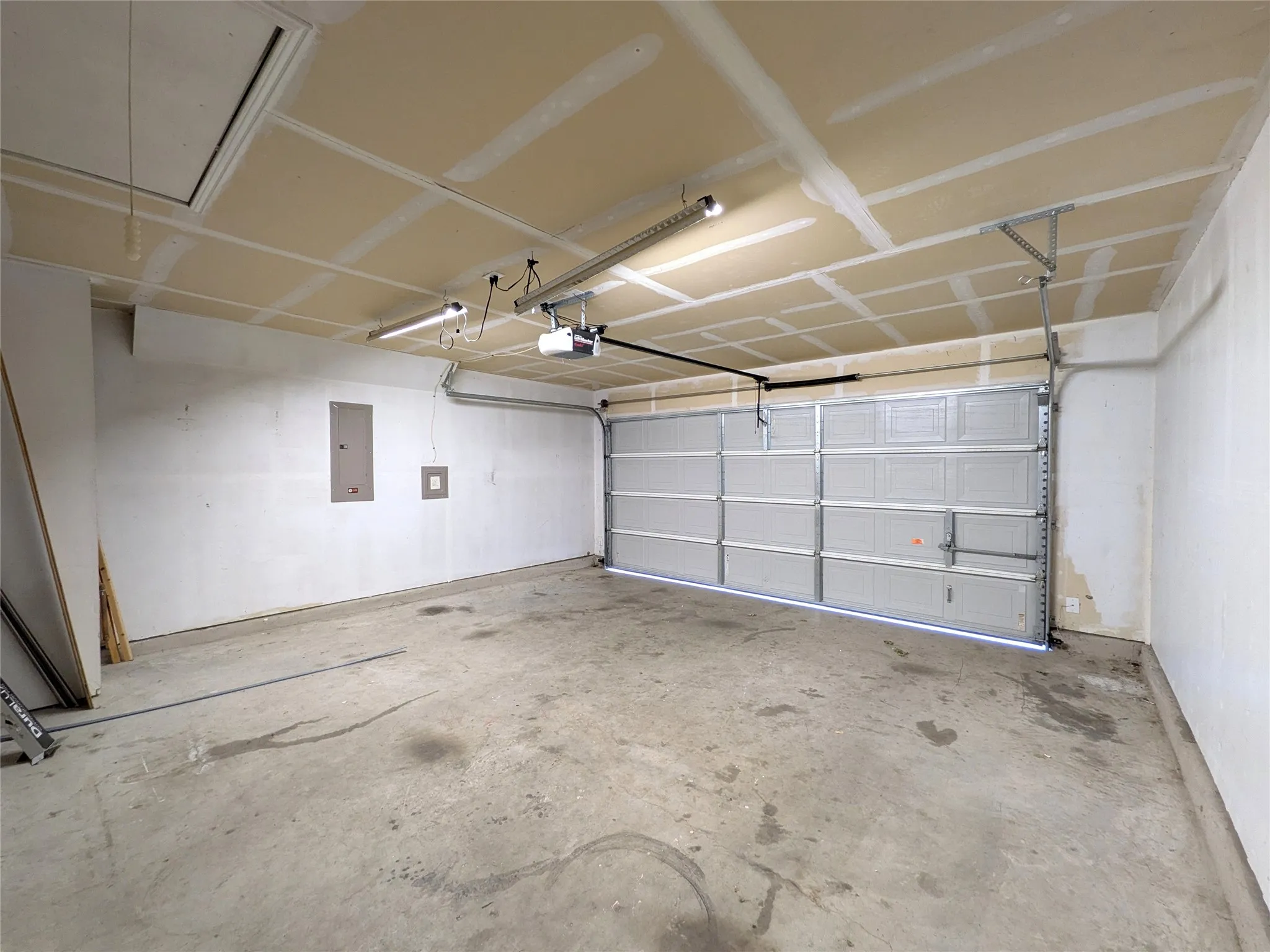 Attached single-car garage featuring a metal overhead door, concrete flooring, and an automatic garage door opener
