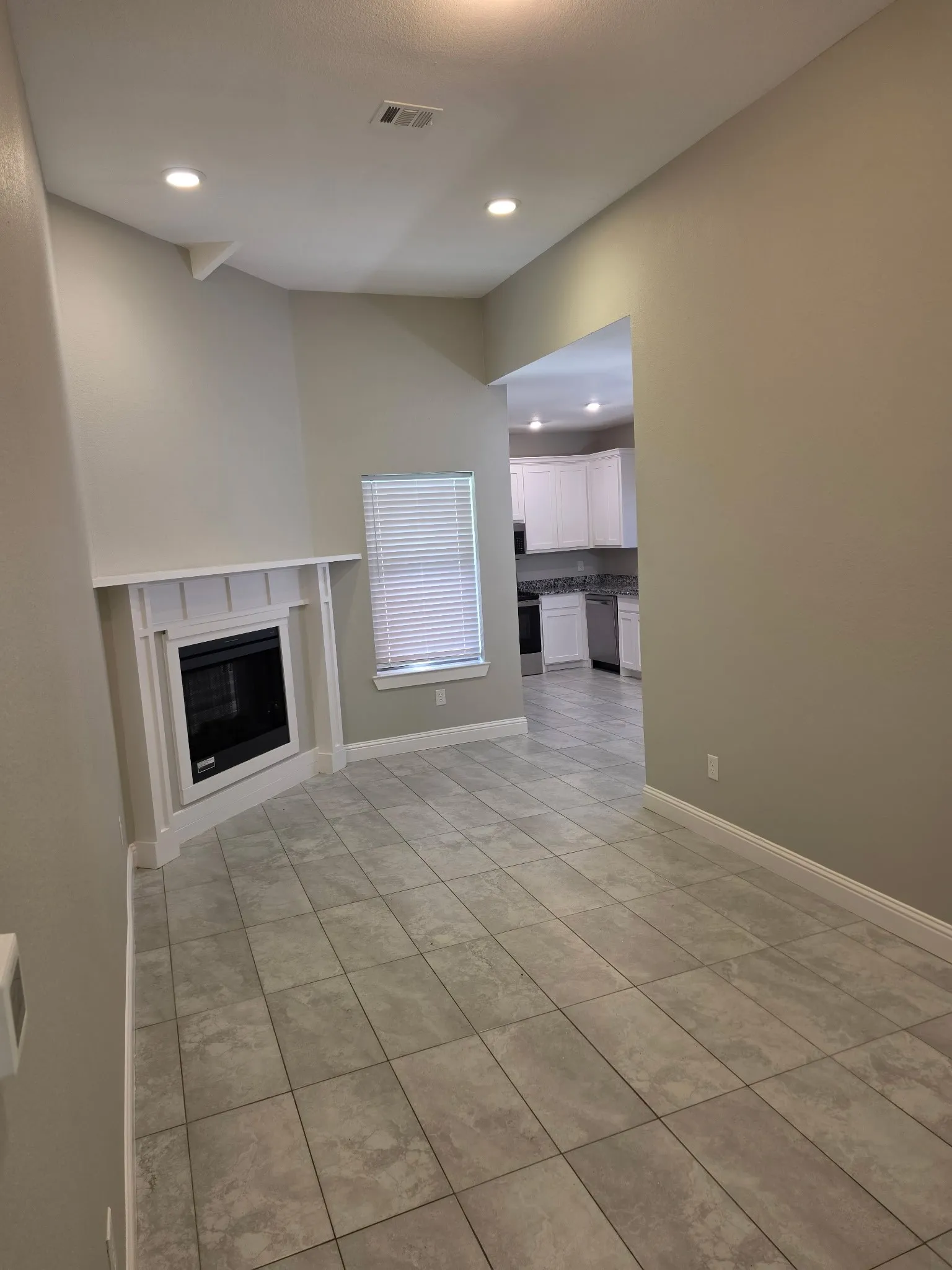 Tile flooring throughout, recessed lighting, and a corner fireplace with white surround
